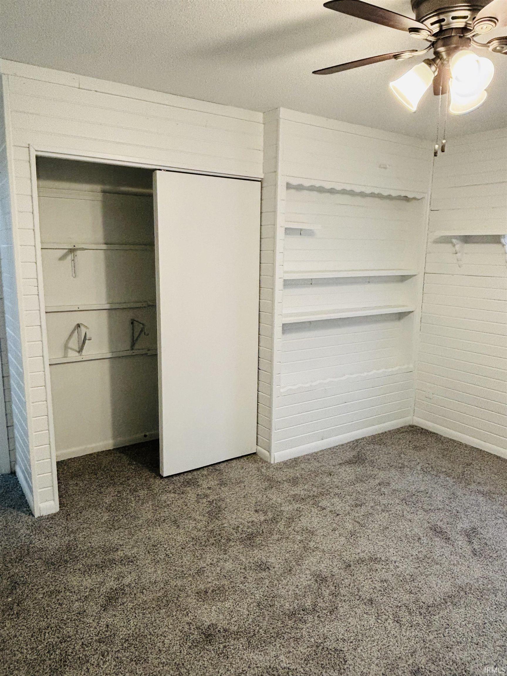 Unfurnished bedroom with a closet, dark colored carpet, a ceiling fan, and a textured ceiling