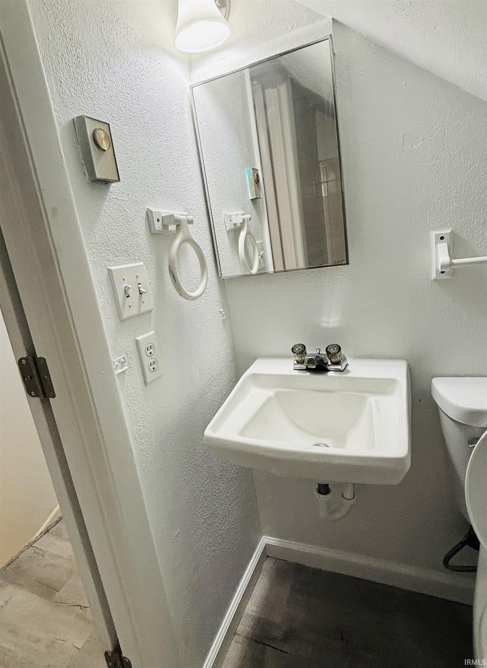 Half bath with a textured wall and toilet