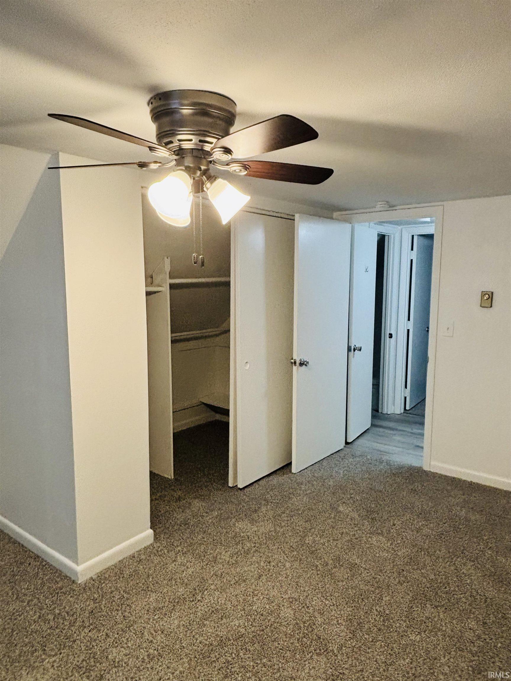 Unfurnished bedroom featuring dark carpet, a textured ceiling, a ceiling fan, and a closet