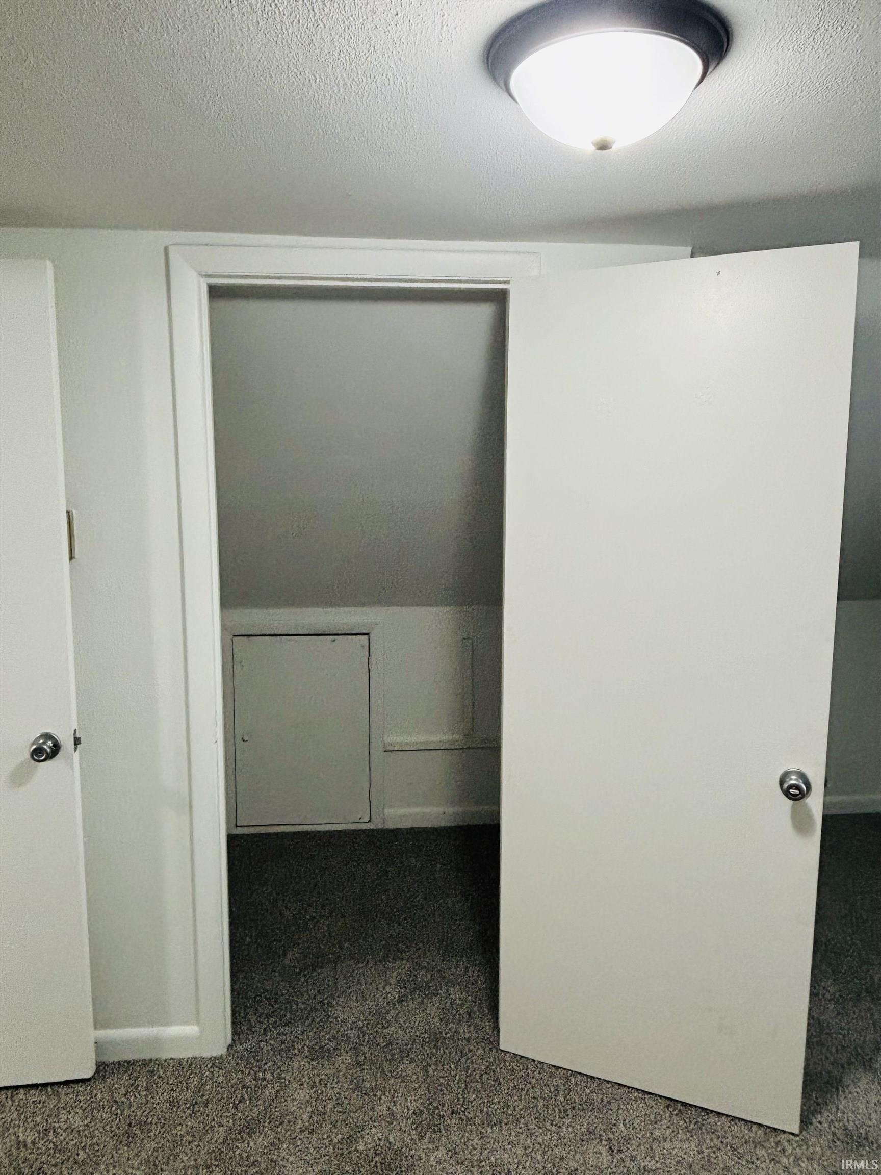 Corridor with dark colored carpet and a textured ceiling