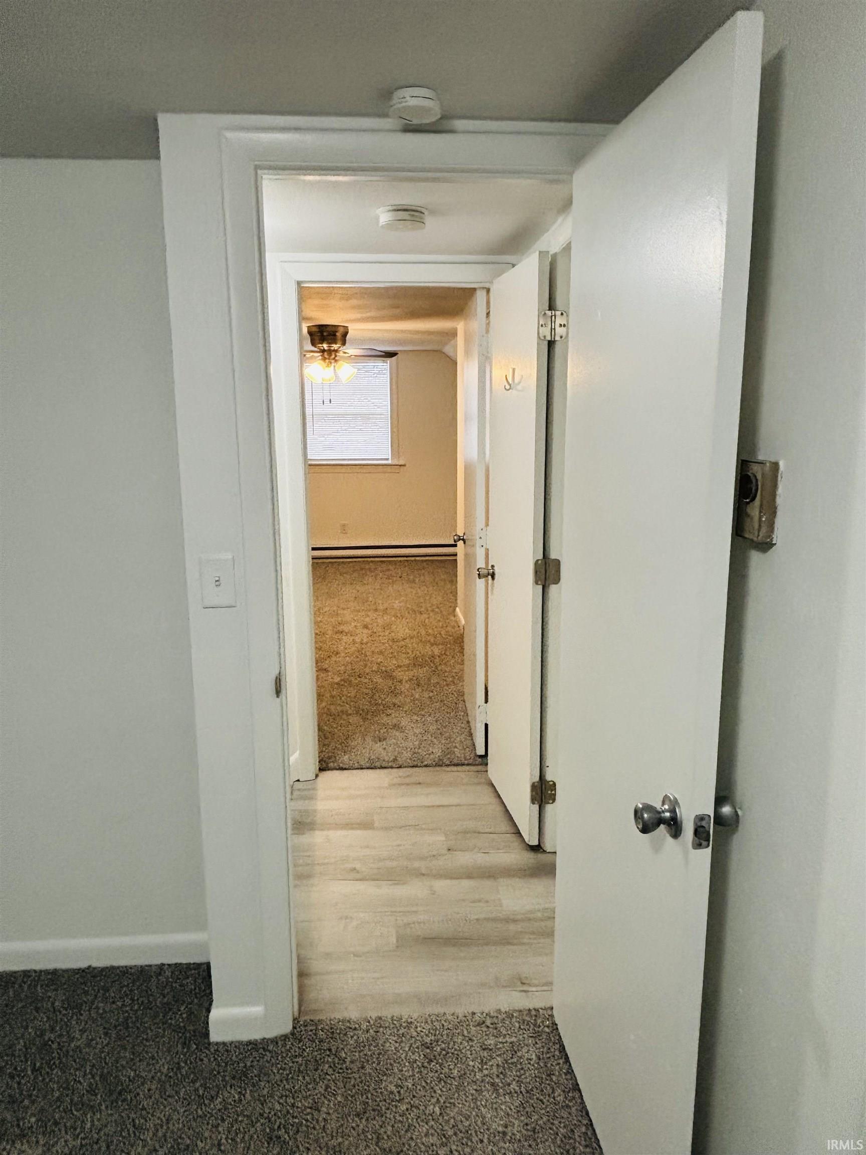 Hall featuring light carpet and light wood-style flooring