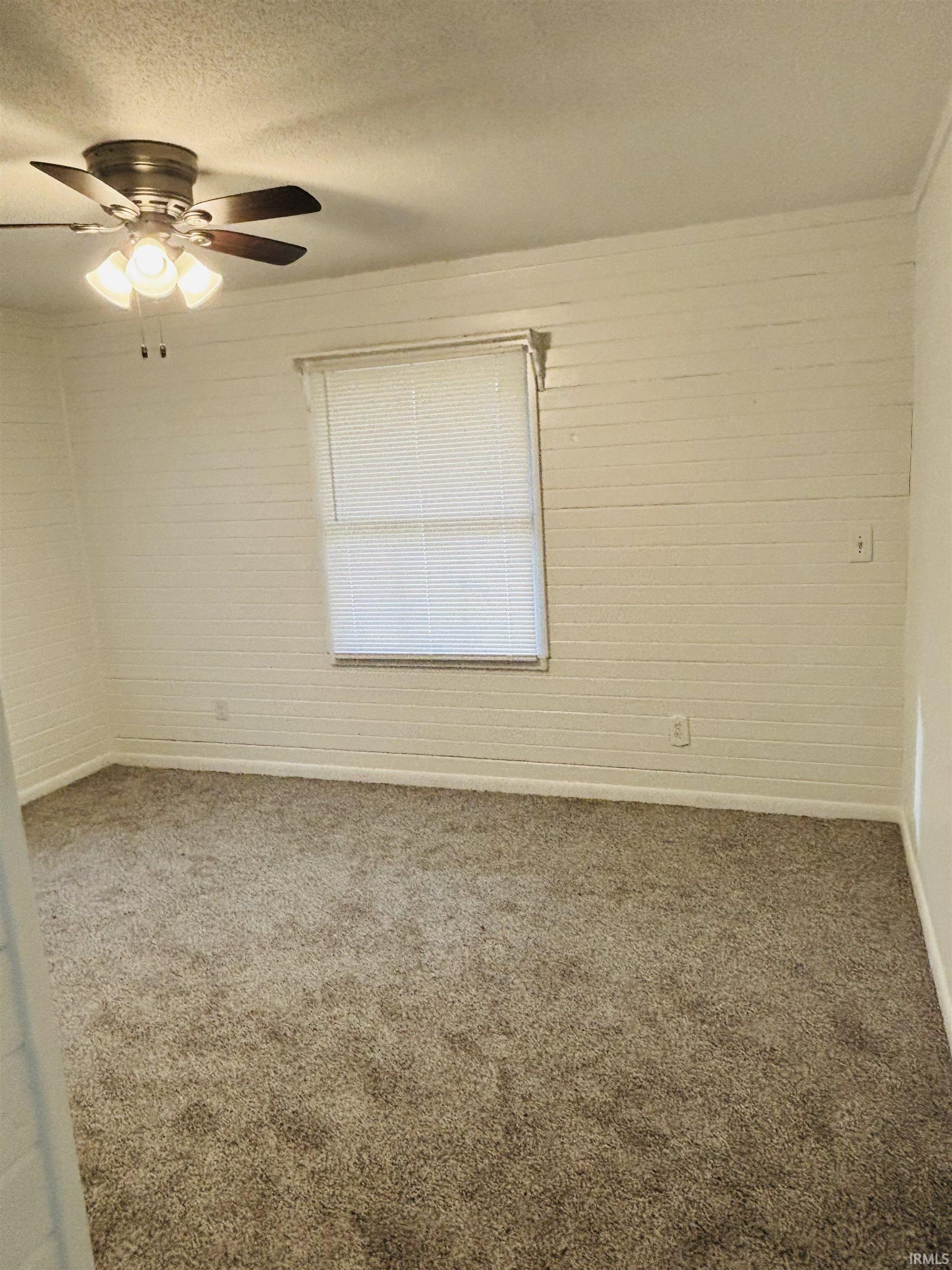 Empty room featuring carpet, ceiling fan, and a textured ceiling