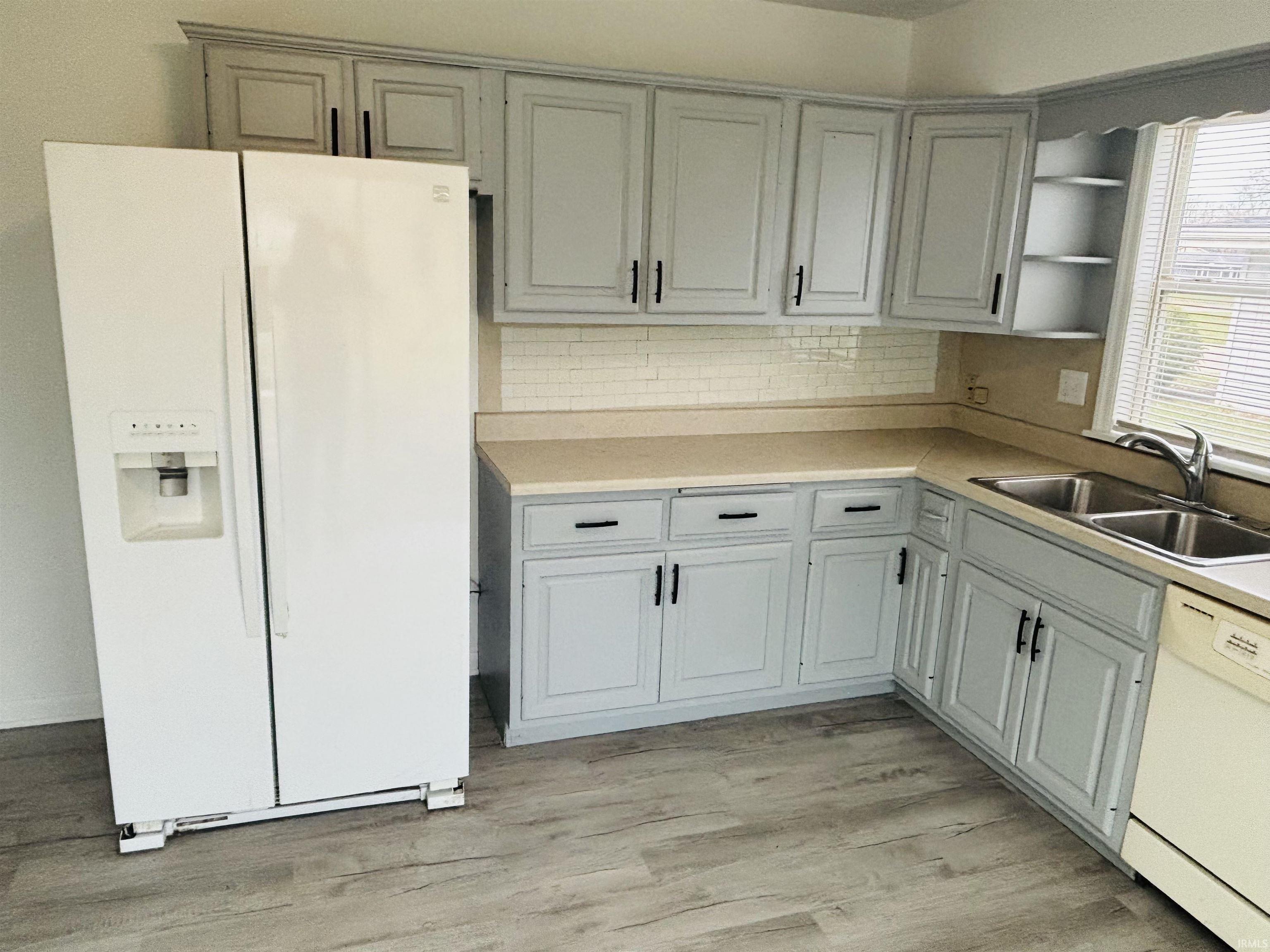 Kitchen with white appliances, light countertops, light wood finished floors, open shelves, and backsplash