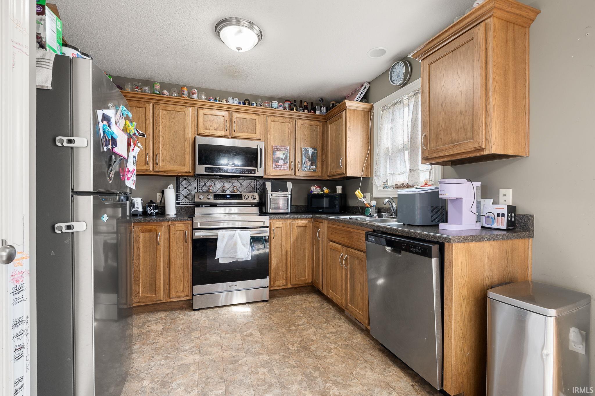 Kitchen featuring dark countertops, stainless steel appliances, and wood finish cabinetry