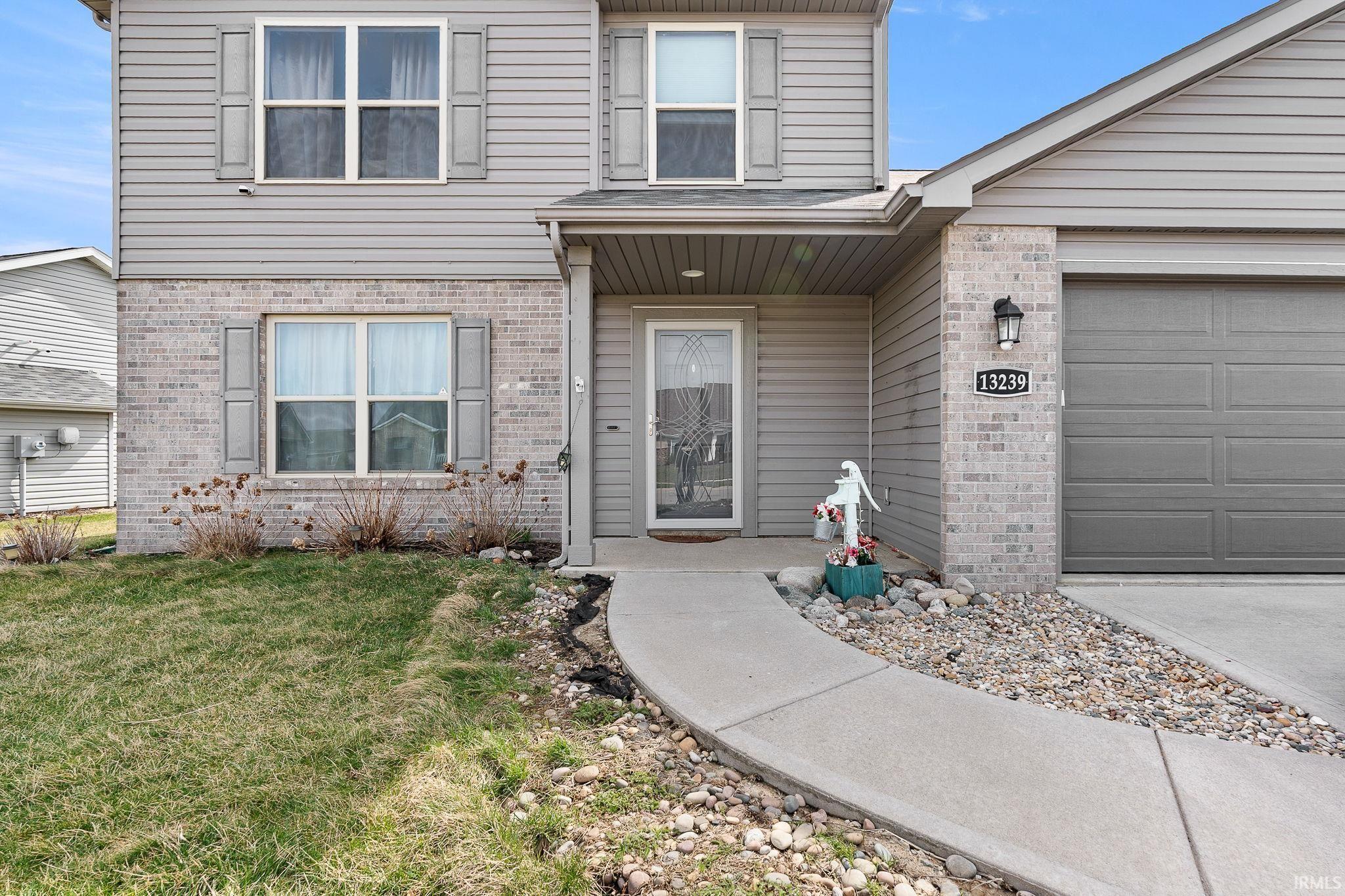 Entrance to property with brick siding, a yard, and a garage