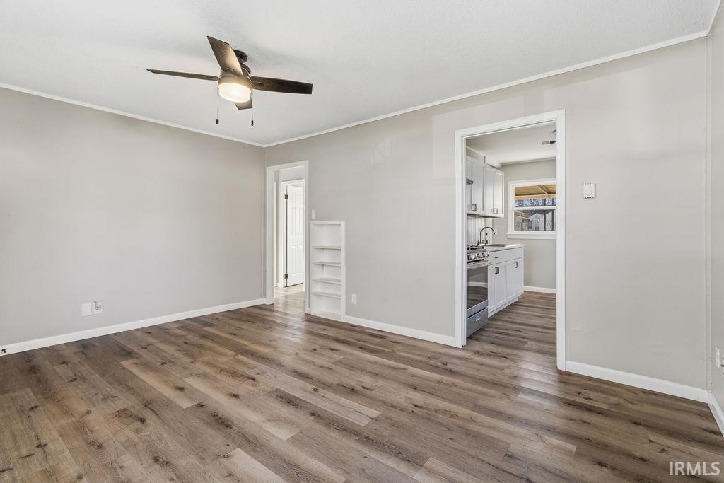 Unfurnished room with ornamental molding, ceiling fan, and dark wood-style floors
