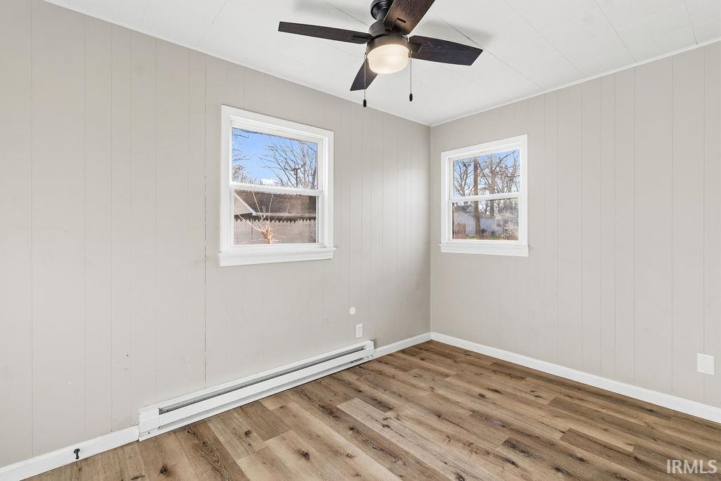 Unfurnished room featuring a baseboard radiator, light wood-style floors, and healthy amount of natural light