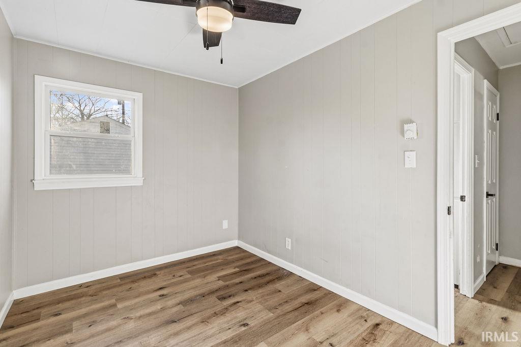 Unfurnished room featuring wood finished floors, a ceiling fan, and wood walls