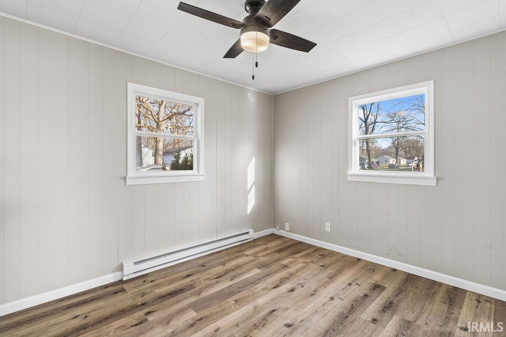 Unfurnished room featuring a baseboard heating unit, light wood-style floors, and ceiling fan