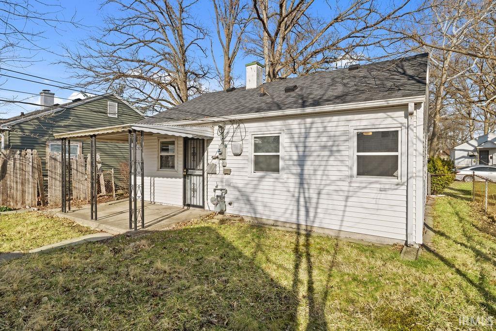 Back of house with a chimney, a patio, and a shingled roof