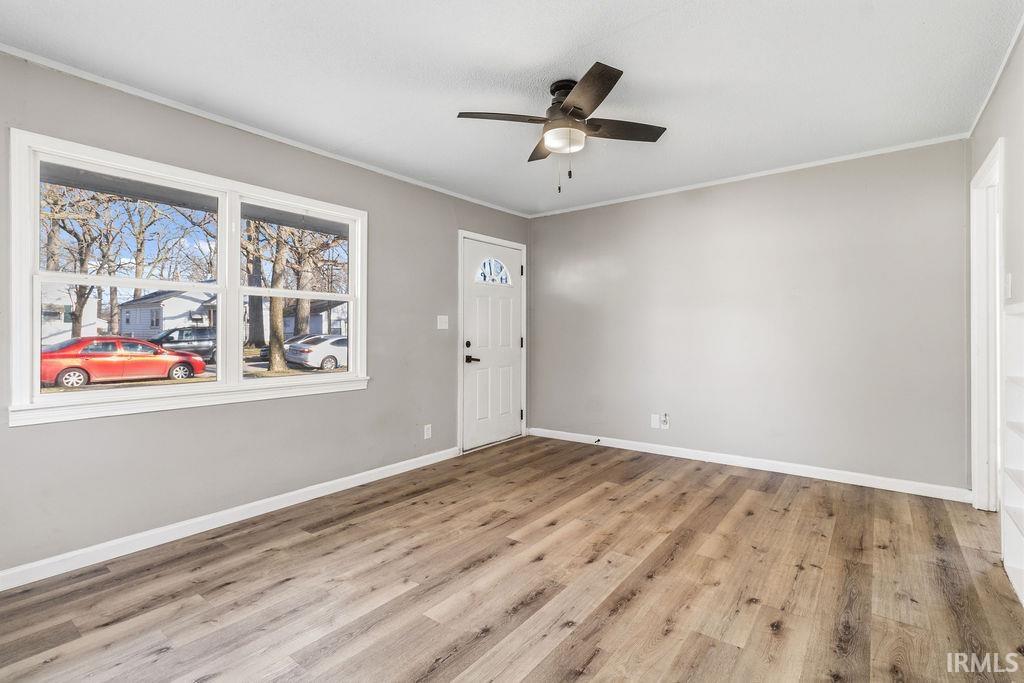 Foyer entrance featuring a ceiling fan, light wood-style flooring, and ornamental molding