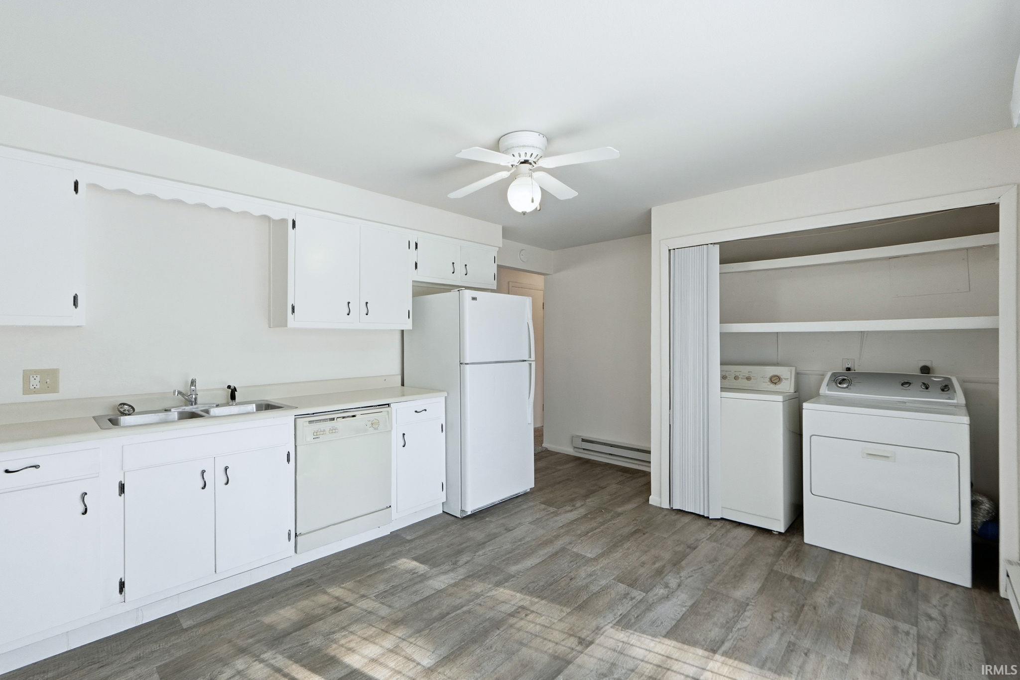 Kitchen with light countertops, white appliances, washing machine and clothes dryer, ceiling fan, and light wood-type flooring