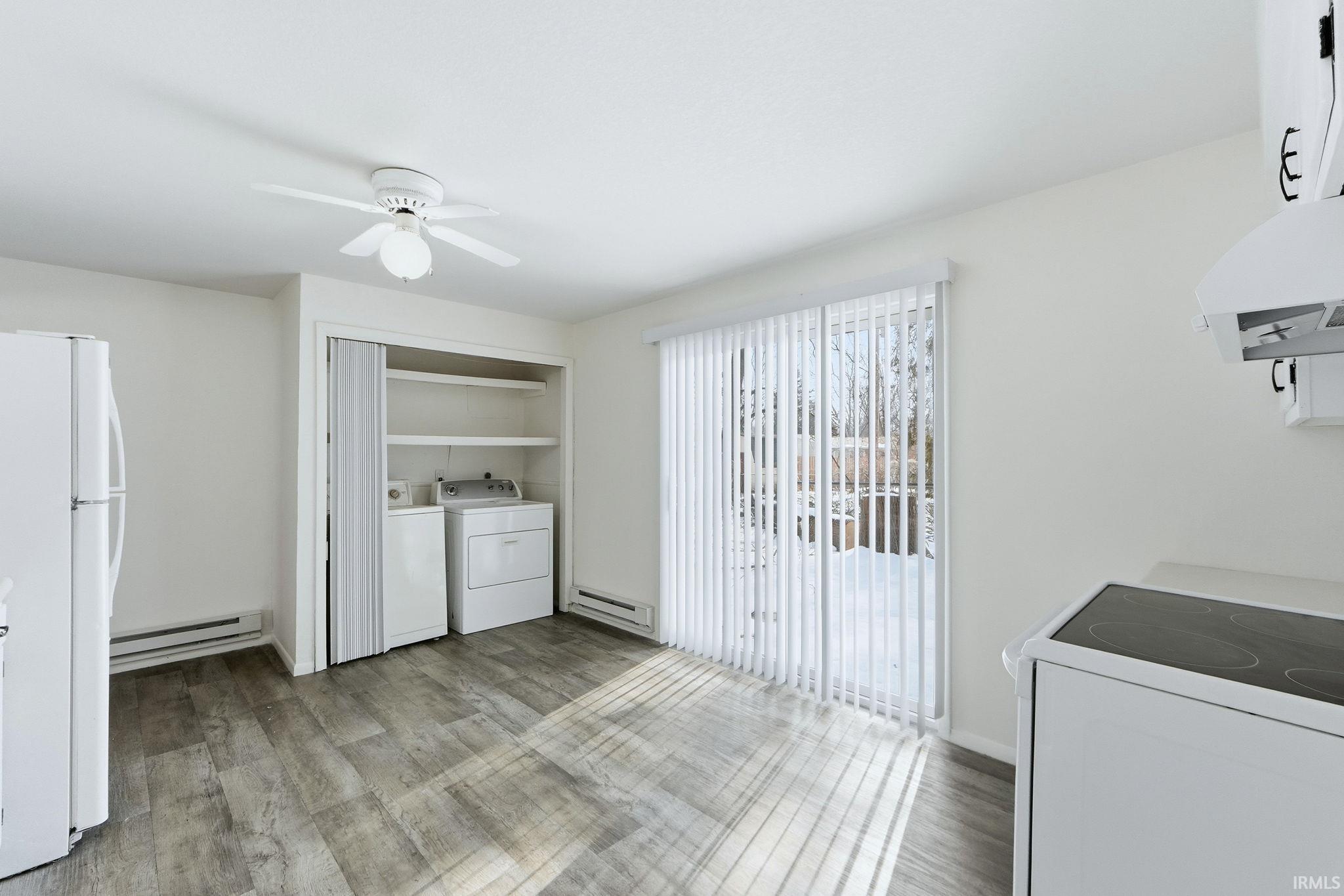Laundry area featuring baseboard heating, light wood finished floors, washing machine and clothes dryer, and a ceiling fan