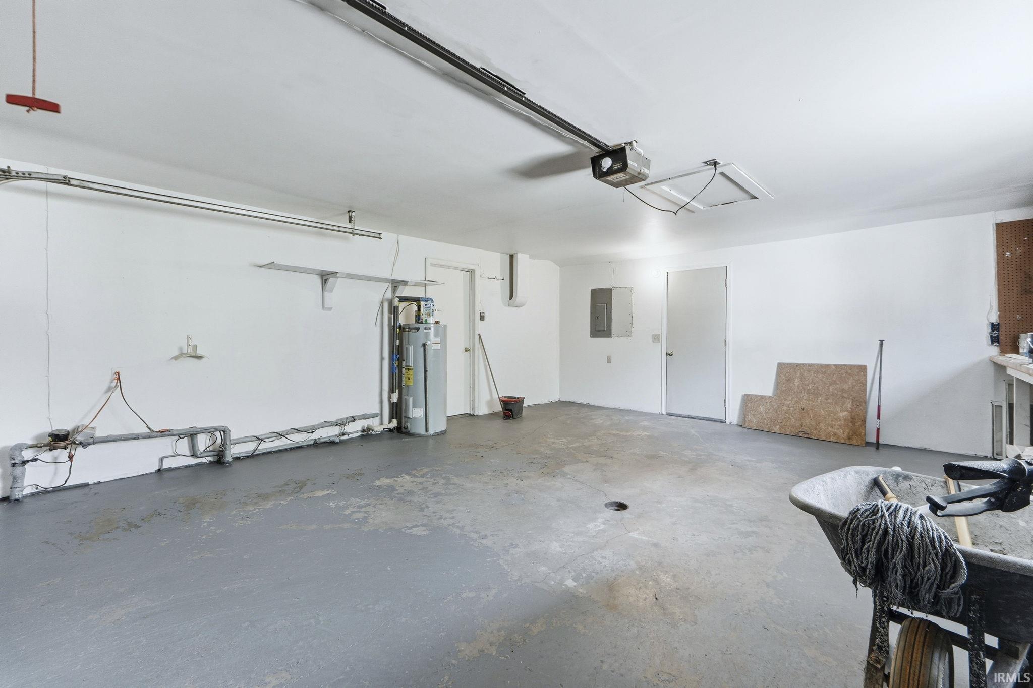 Garage featuring electric water heater, a garage door opener, and electric panel