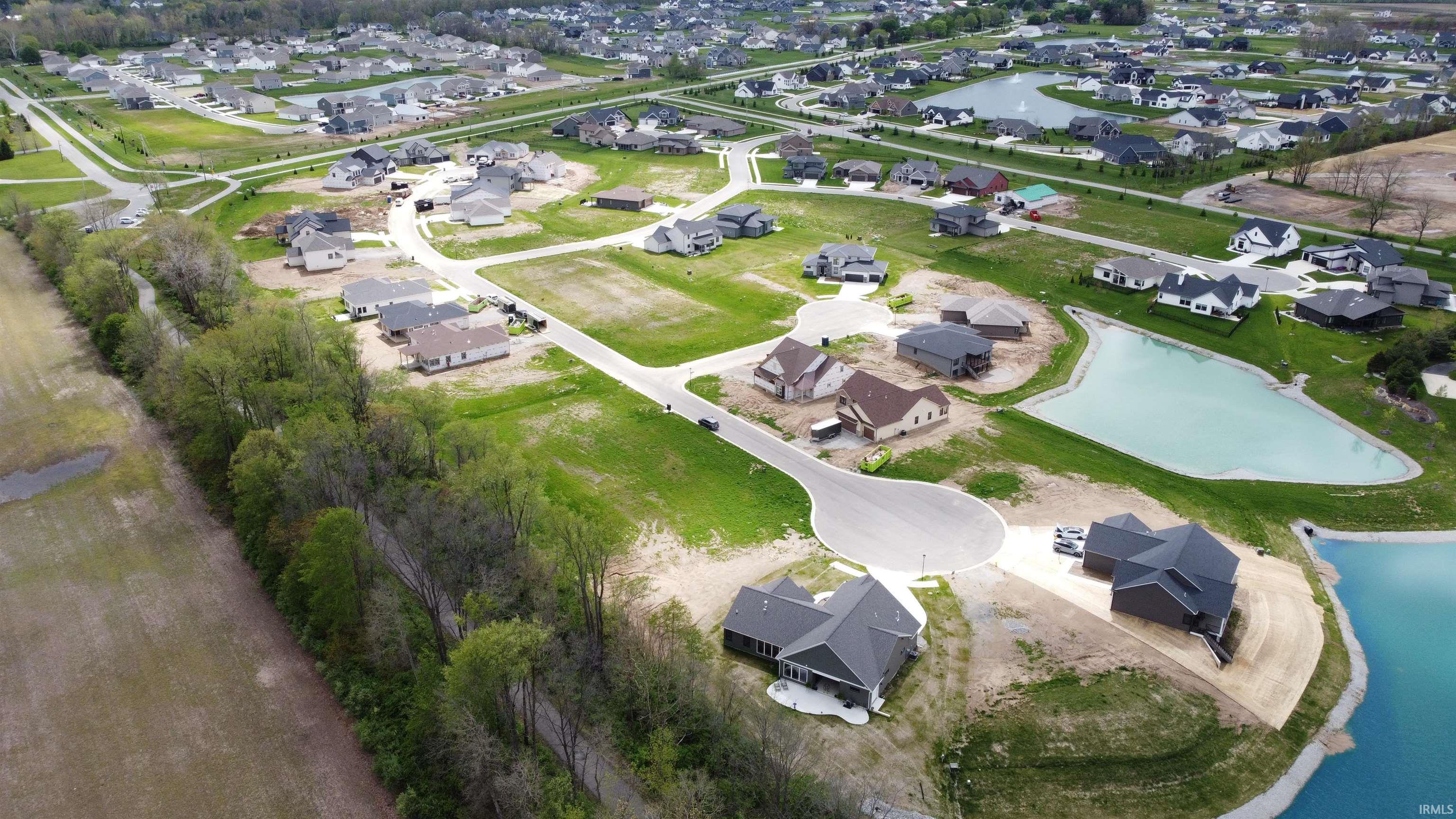 Aerial perspective showcasing a residential development with numerous single-story homes, many featuring dark shingle roofs