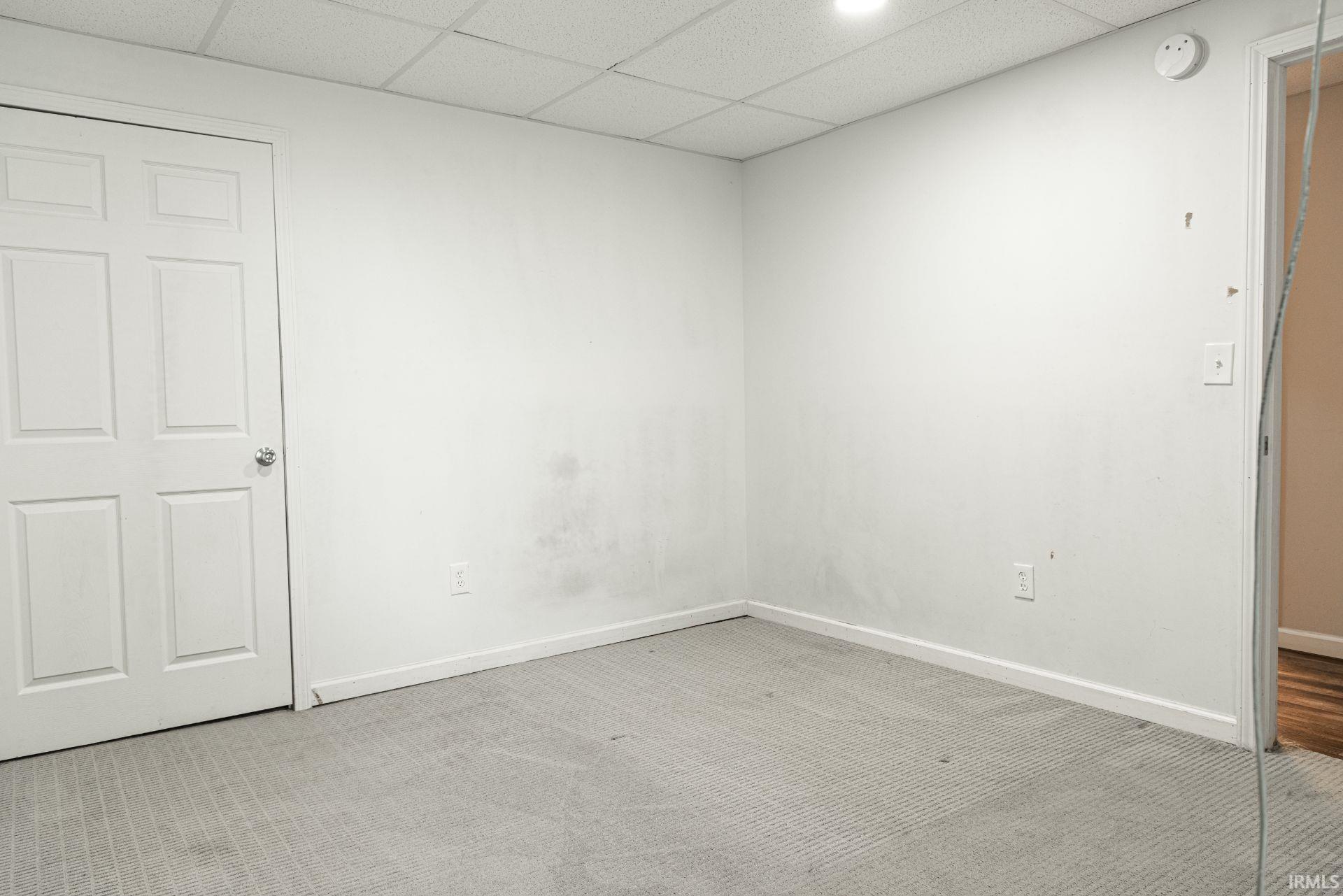 Unfurnished bedroom featuring a paneled ceiling and light carpet