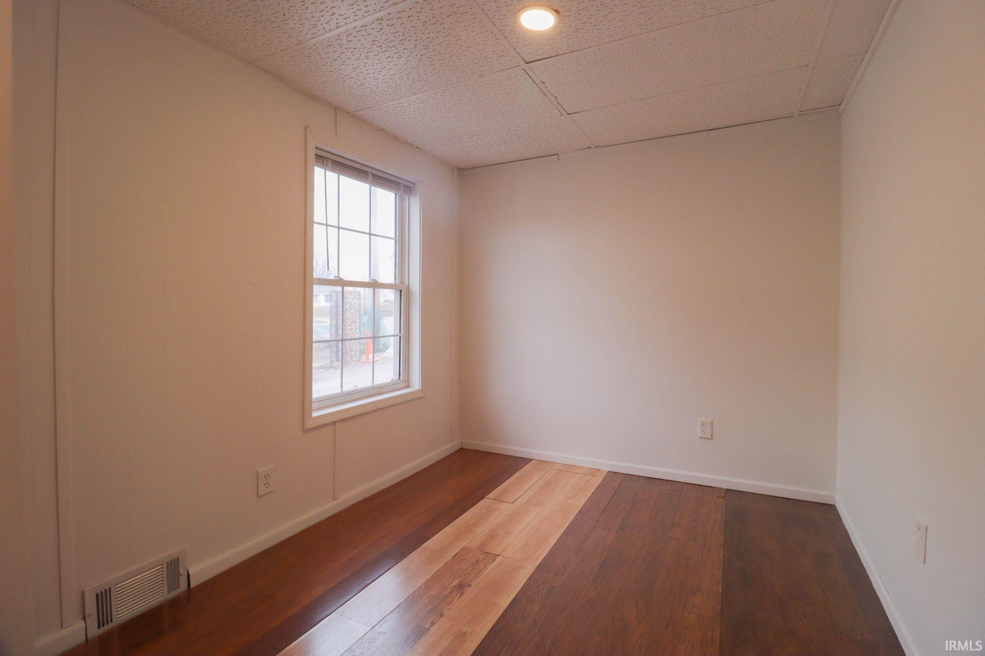 Unfurnished room featuring wood-type flooring and a drop ceiling
