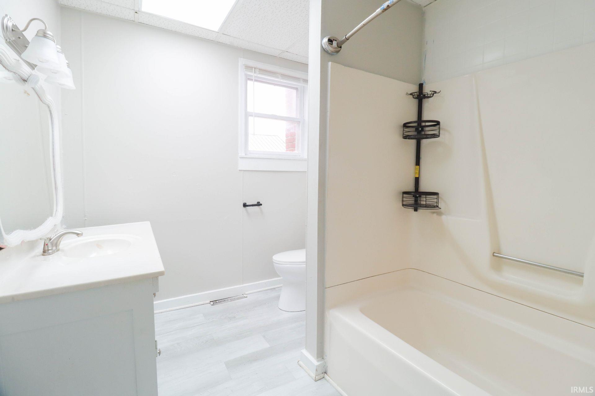 Full bathroom with vanity, a drop ceiling, tub / shower combination, and light wood-style flooring