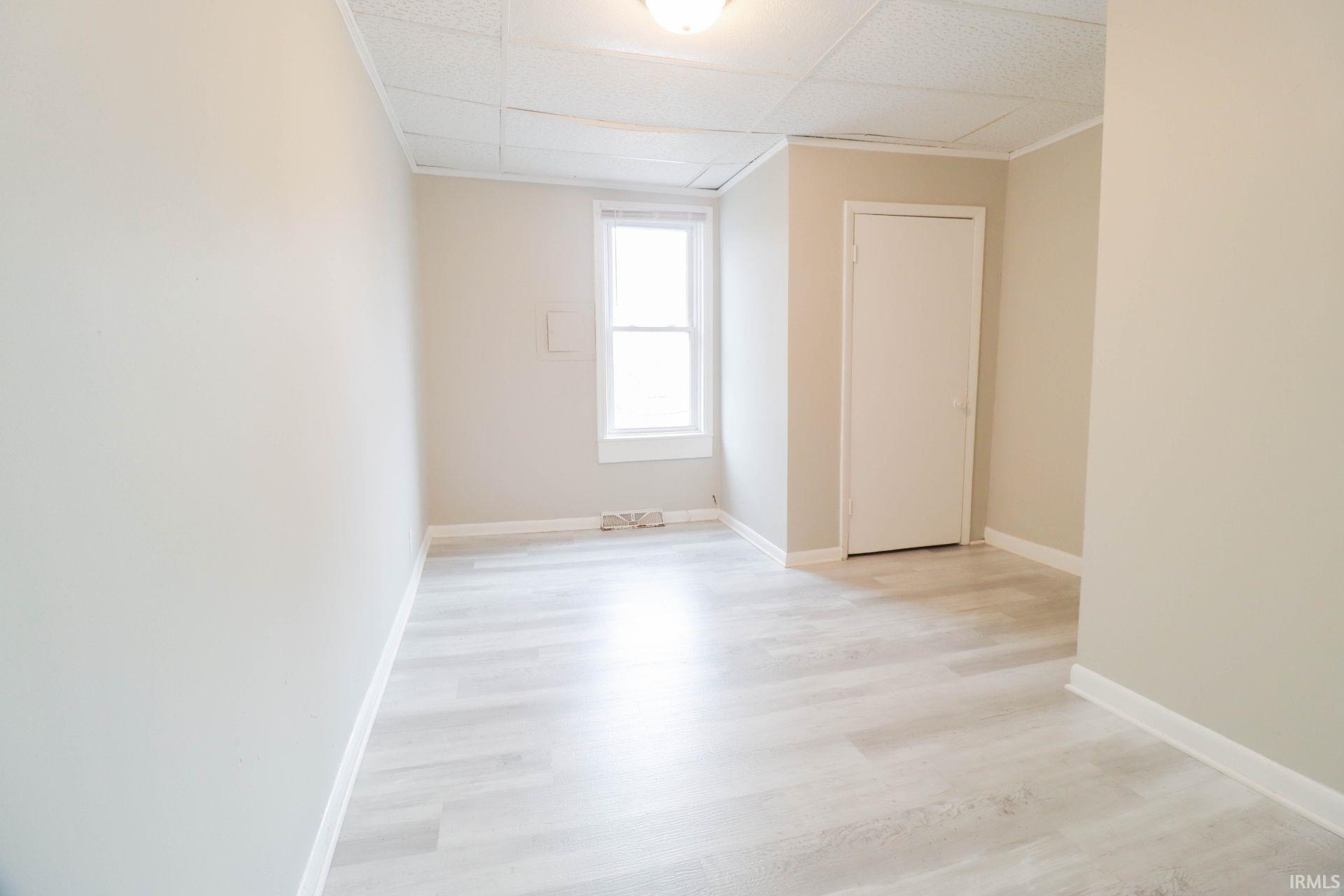 Unfurnished room with light wood finished floors and a paneled ceiling