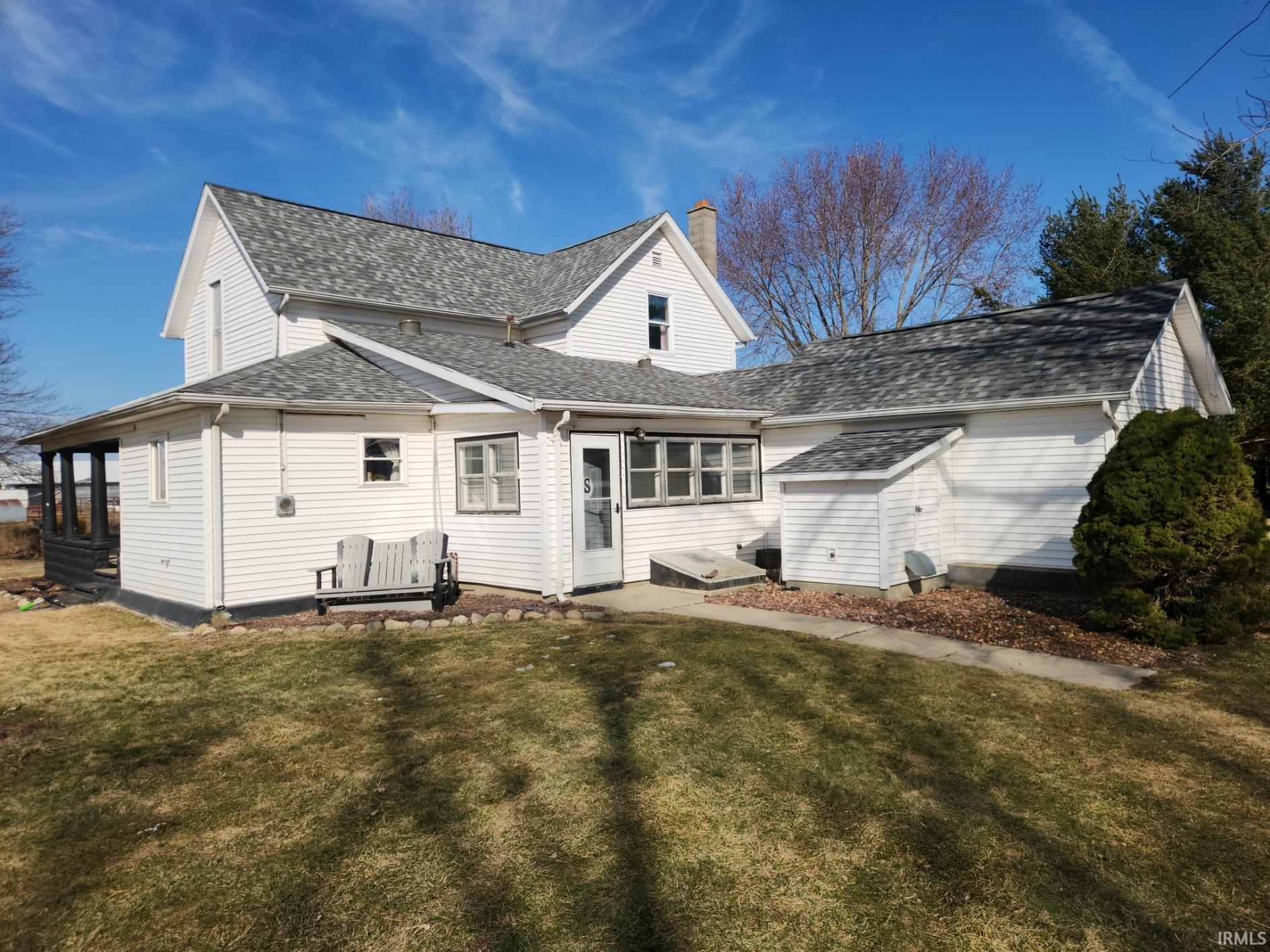 Rear view of house featuring roof with shingles, a yard, and a chimney