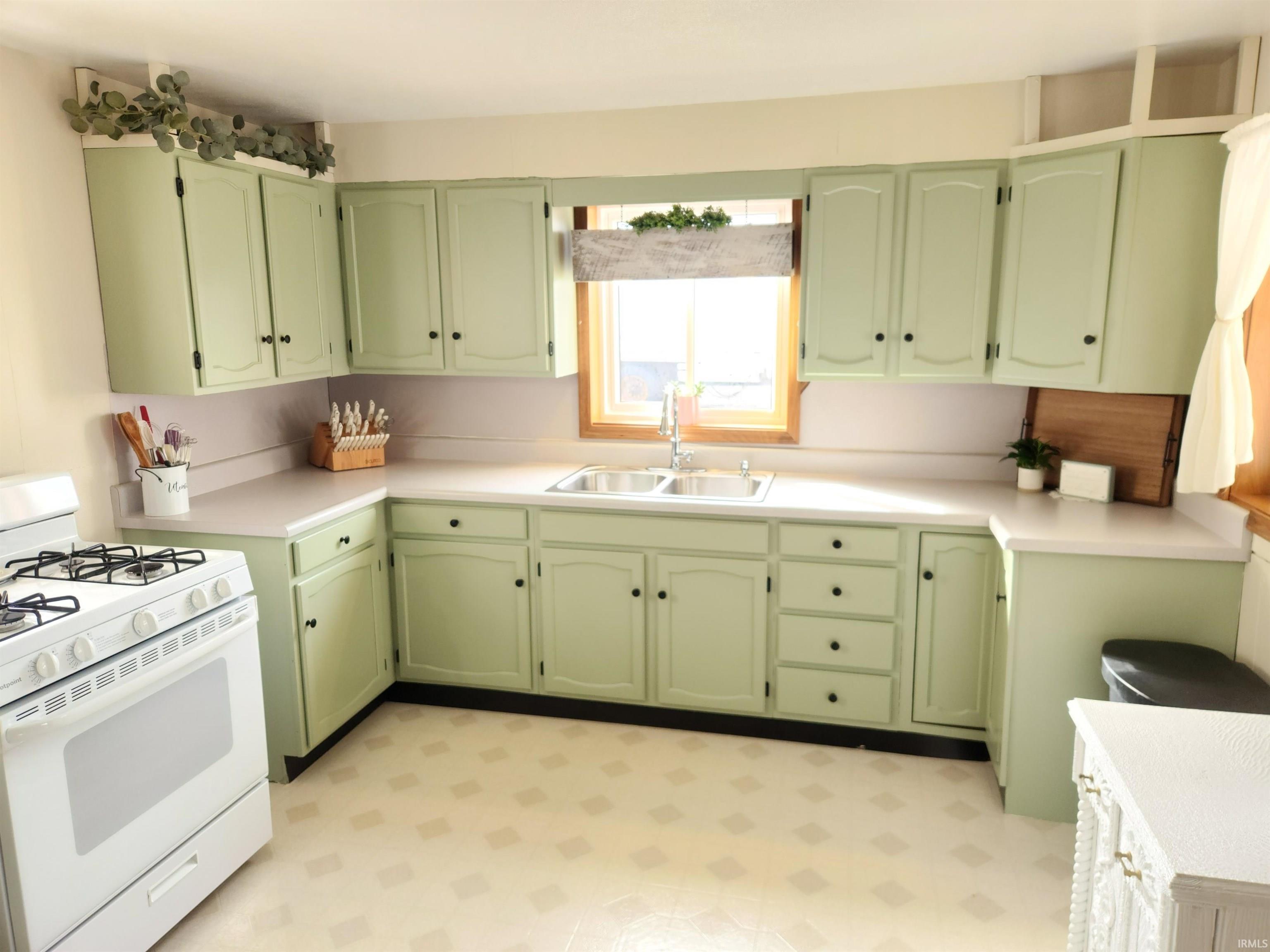 Kitchen featuring green cabinetry, gas range gas stove, light floors, and light countertops