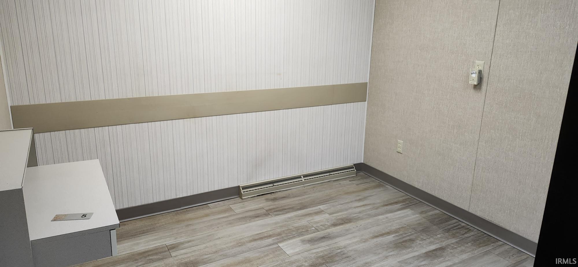 Unfurnished room with light wood finished floors and baseboards