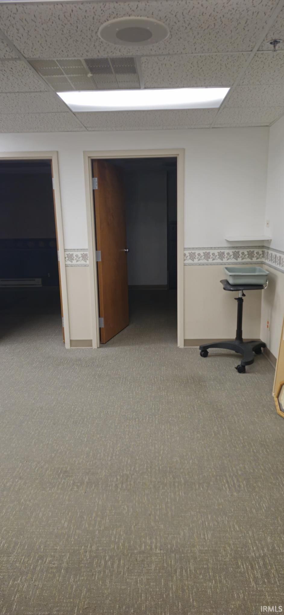 Hallway with a paneled ceiling, carpet, and a baseboard heating unit