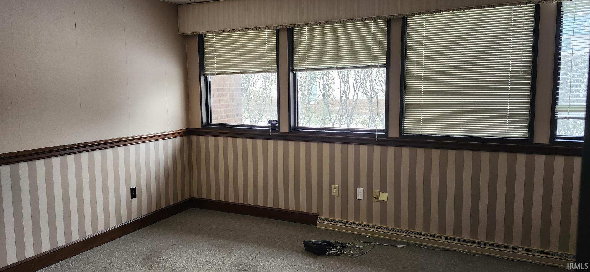 Unfurnished room with a baseboard radiator and wallpapered walls