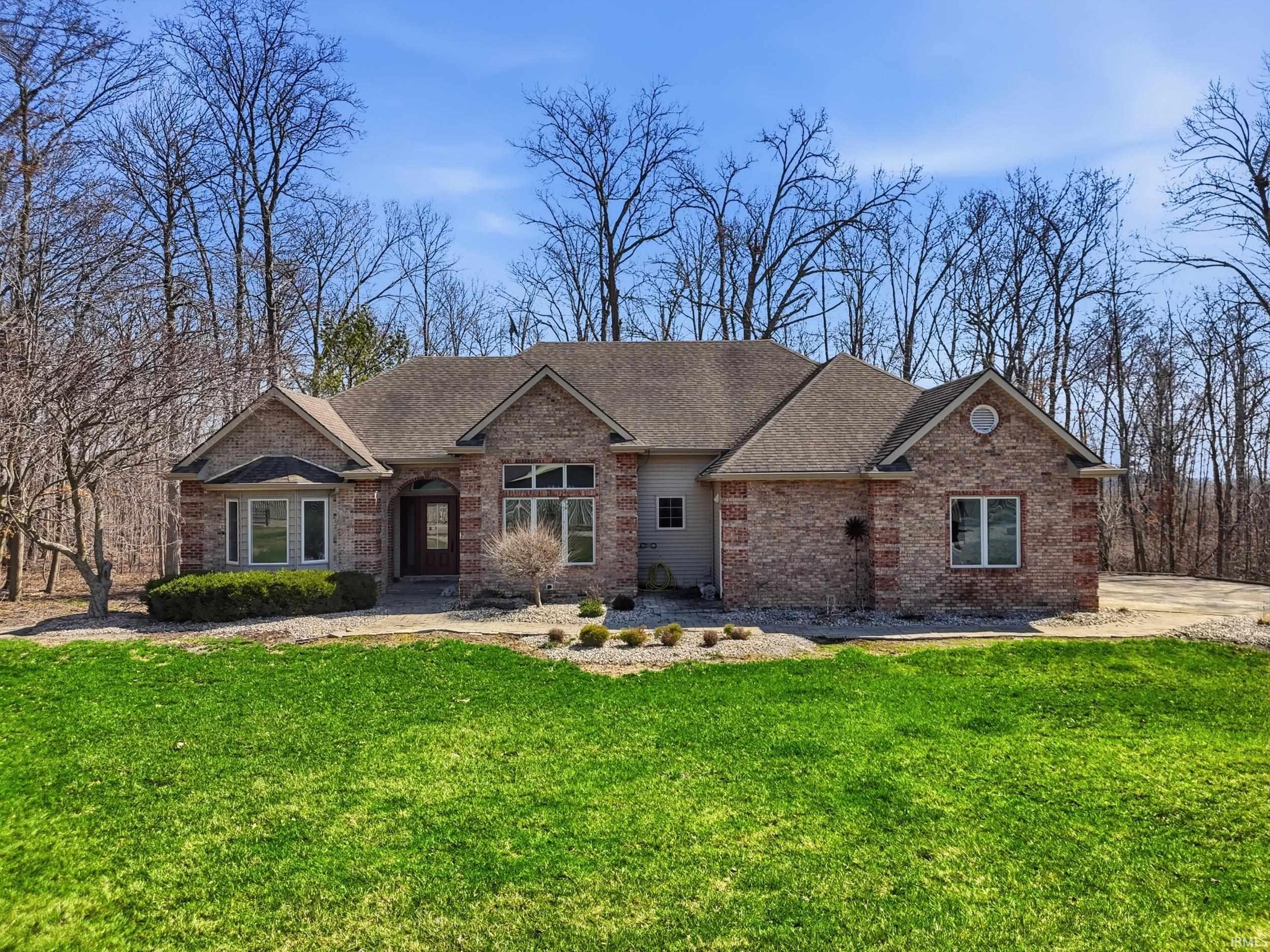 View of front of property with a shingled roof, a front yard, and brick siding