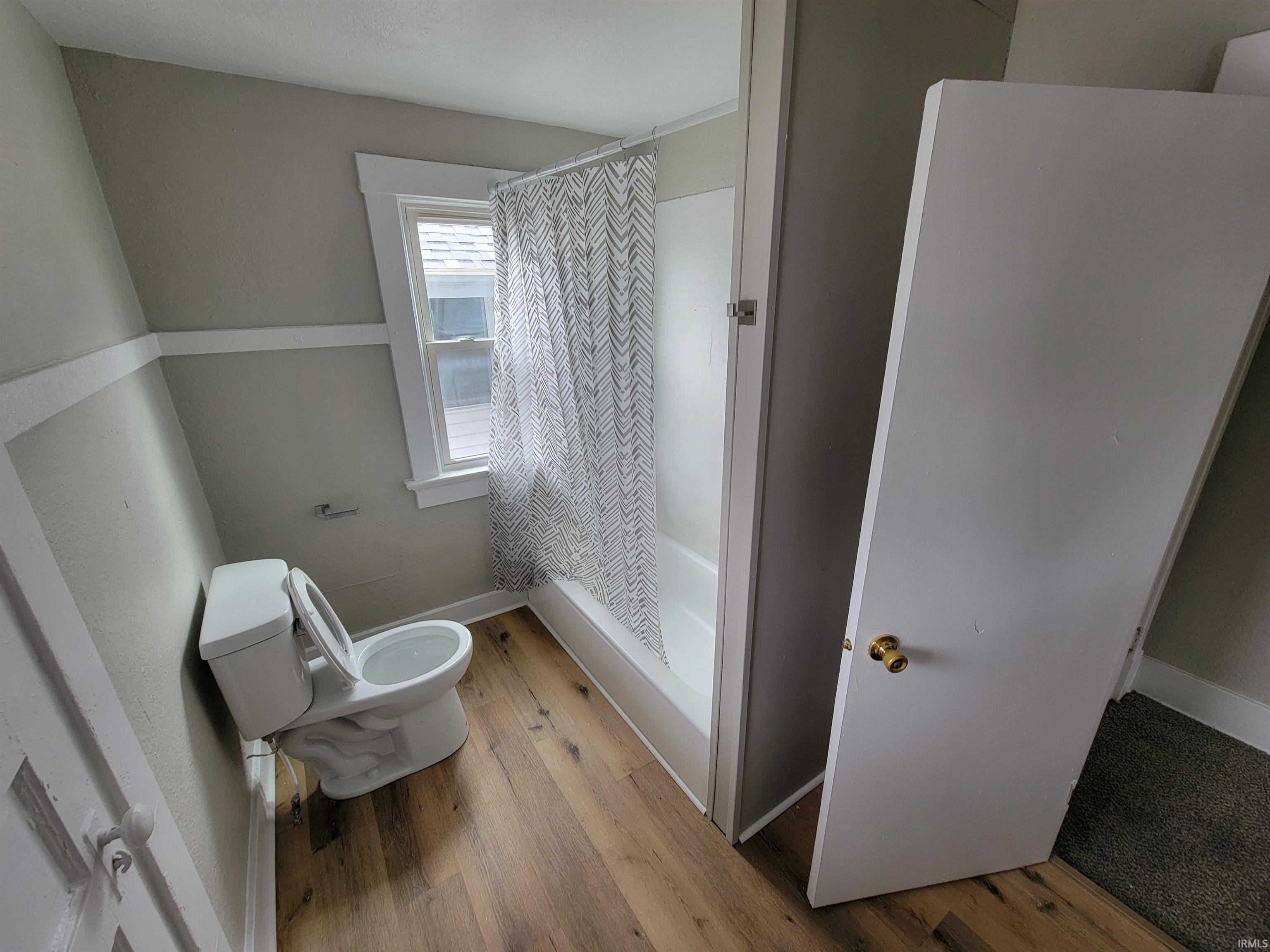 Bathroom with a shower stall and light wood-style floors