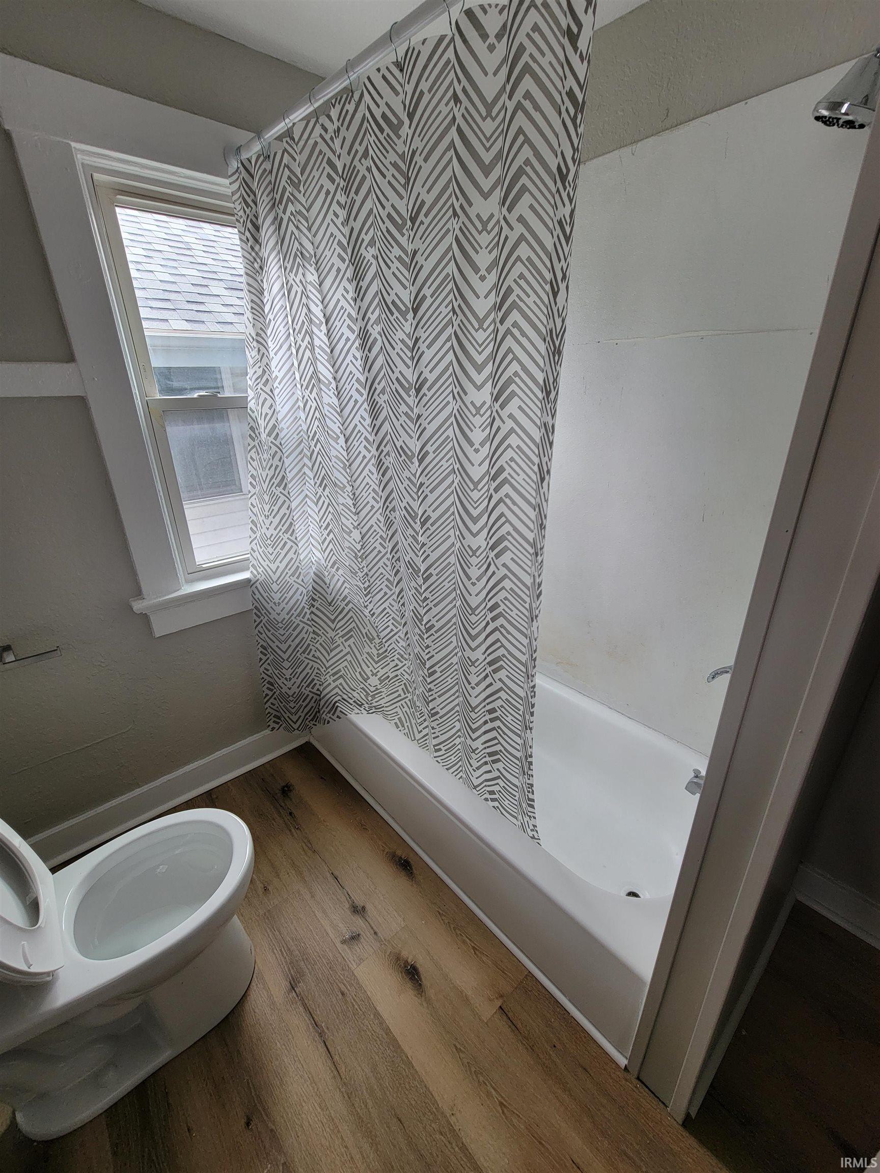 Bathroom featuring light wood-type flooring and shower / tub combo with curtain
