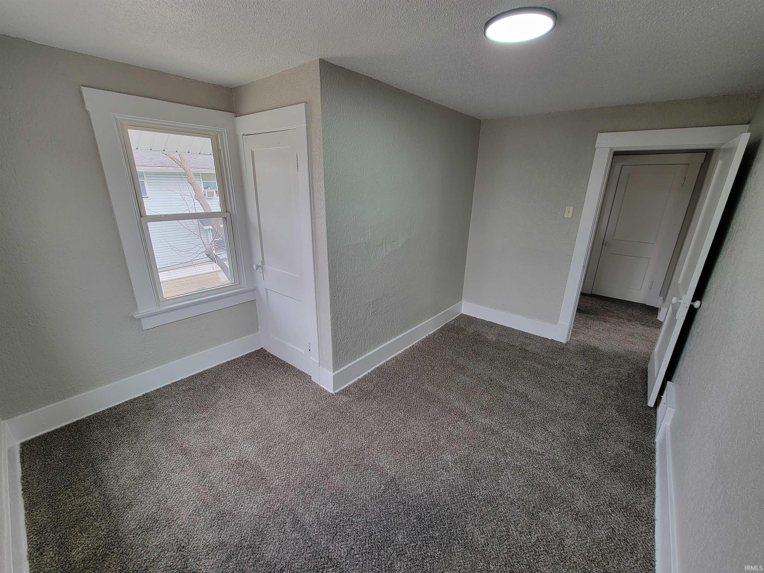 Carpeted empty room with a textured wall and a textured ceiling