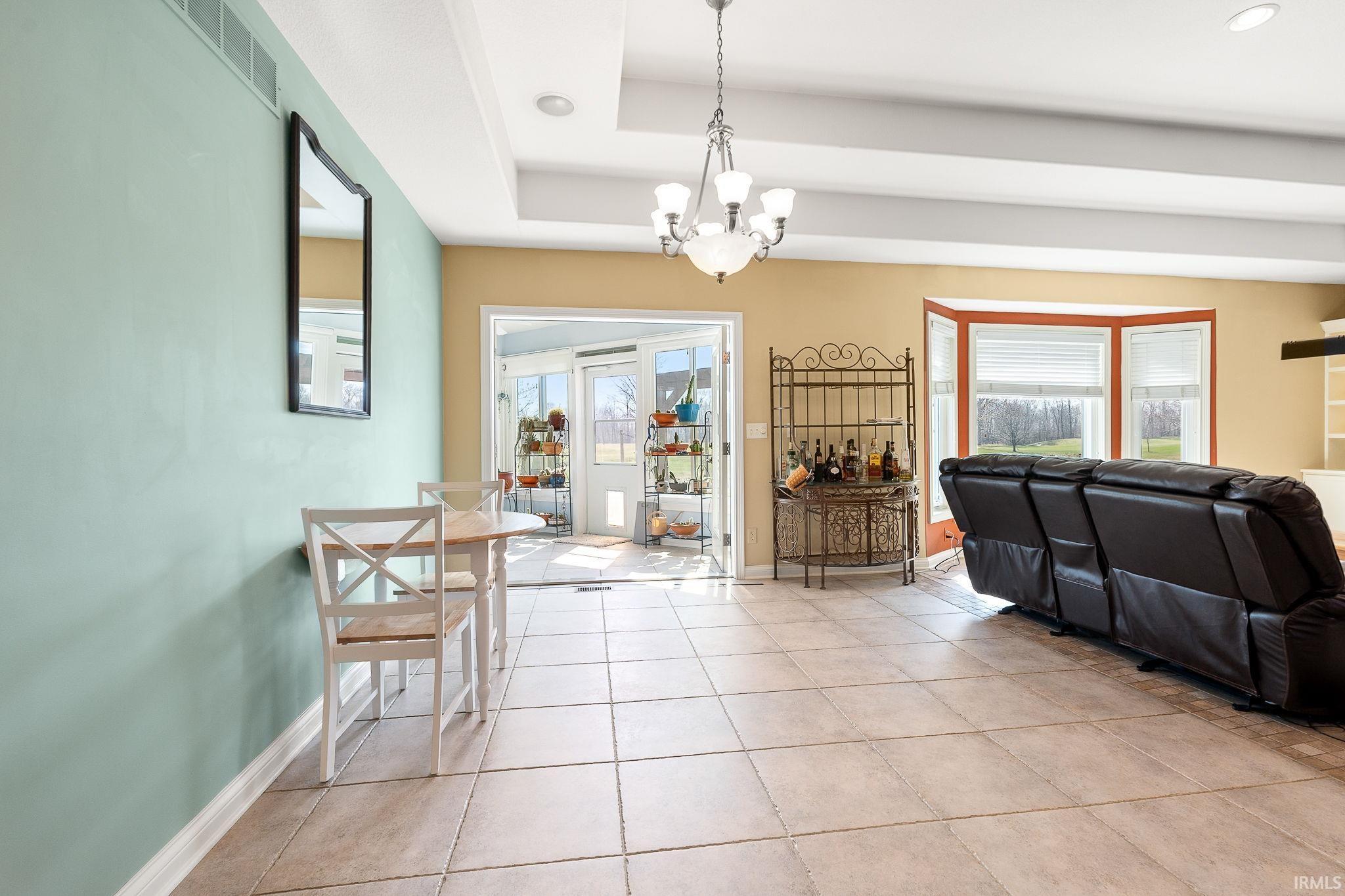 Dining area with a chandelier, light tile patterned flooring, and a tray ceiling
