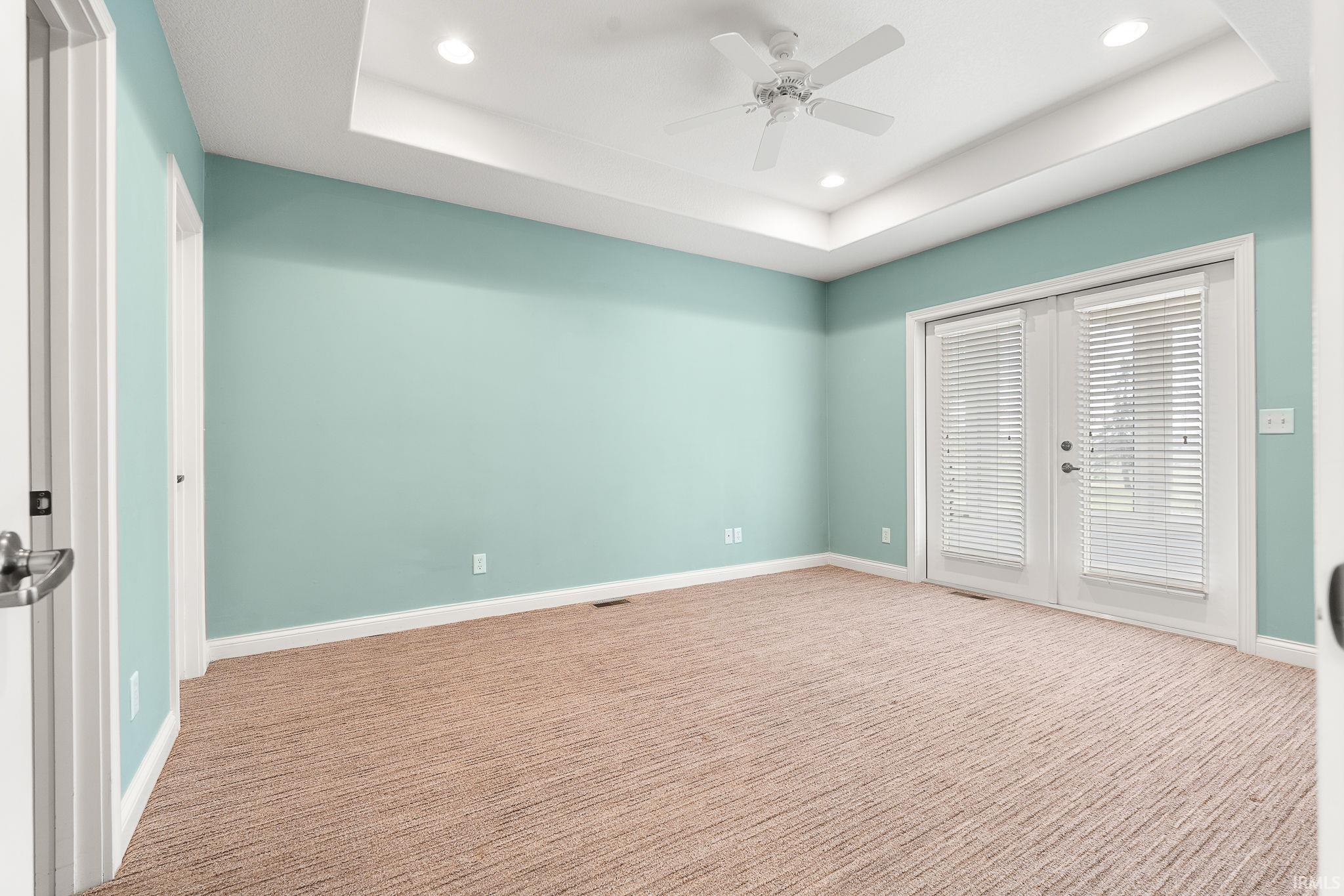 Unfurnished bedroom with french doors, recessed lighting, a tray ceiling, a ceiling fan, and carpet