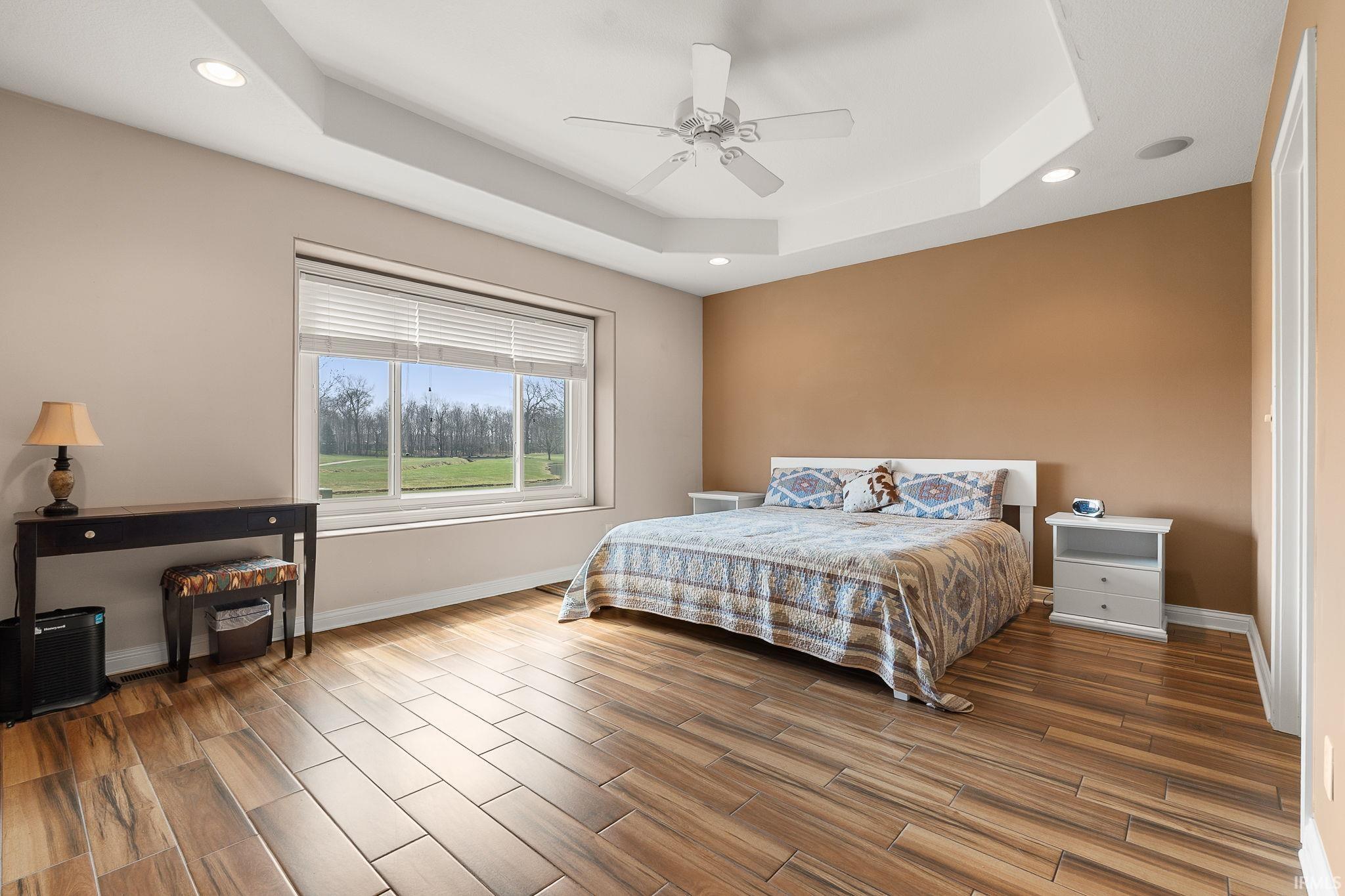 Bedroom with recessed lighting, wood tiled floors, ceiling fan, and a raised ceiling