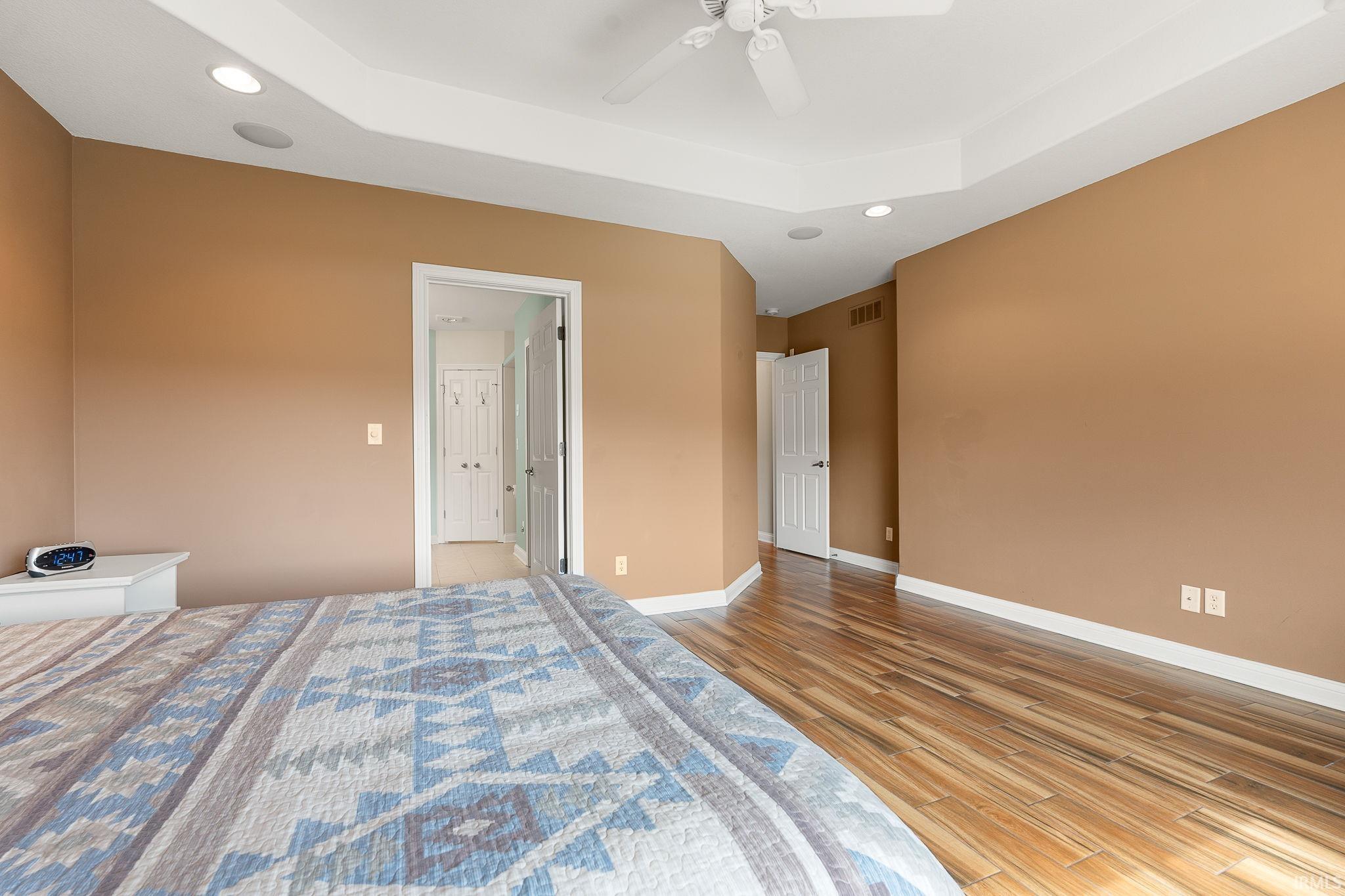 Bedroom with a raised ceiling, recessed lighting, light wood finished floors, and a ceiling fan
