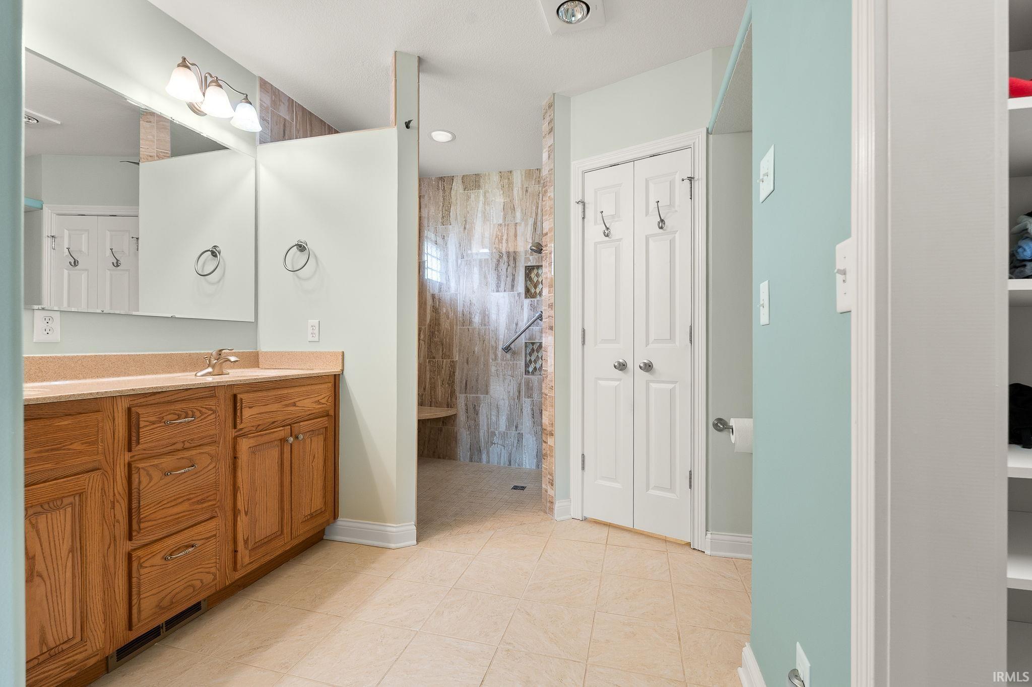 Bathroom featuring vanity, a closet, walk in shower, and light tile patterned floors