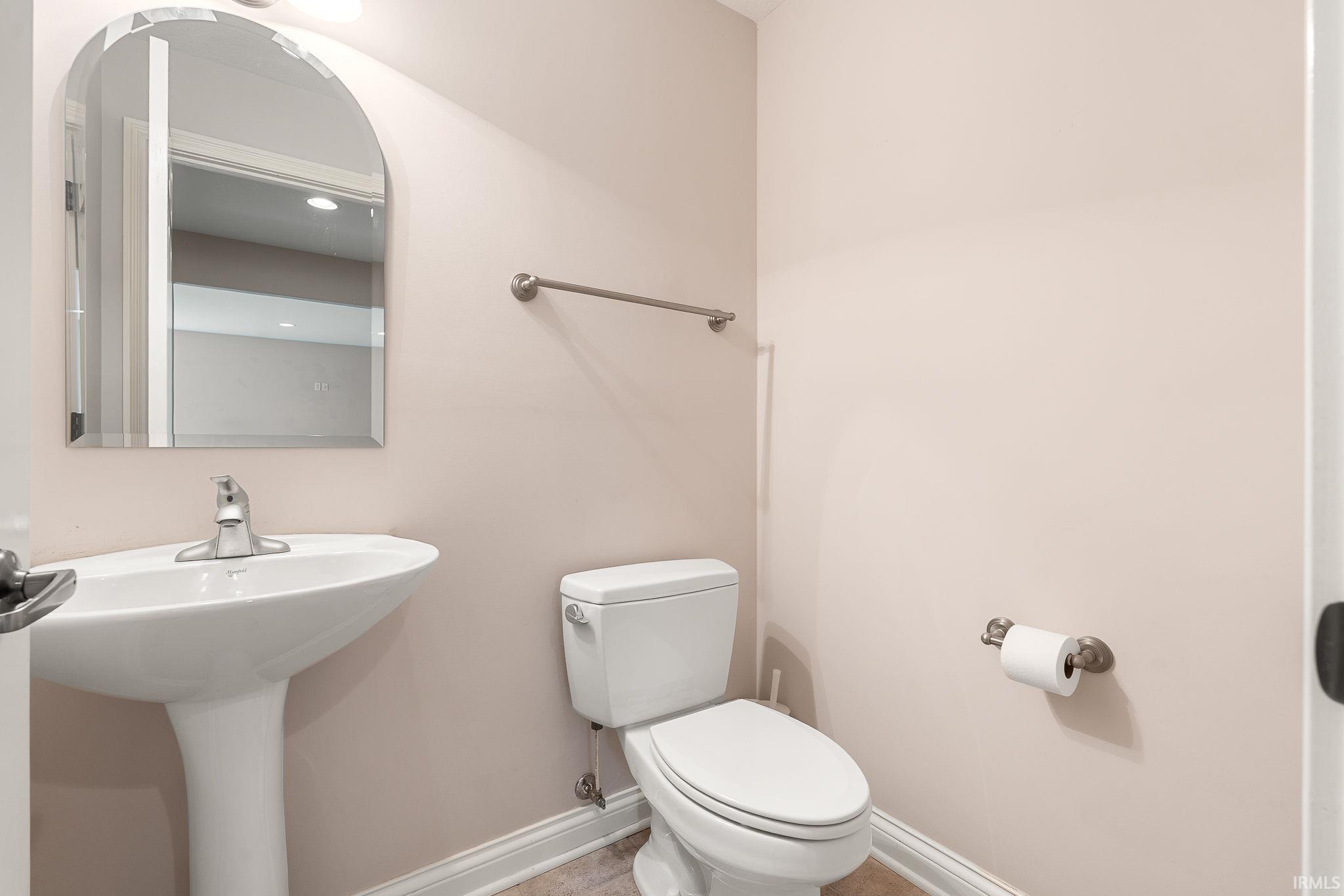 Half bathroom with toilet and baseboards