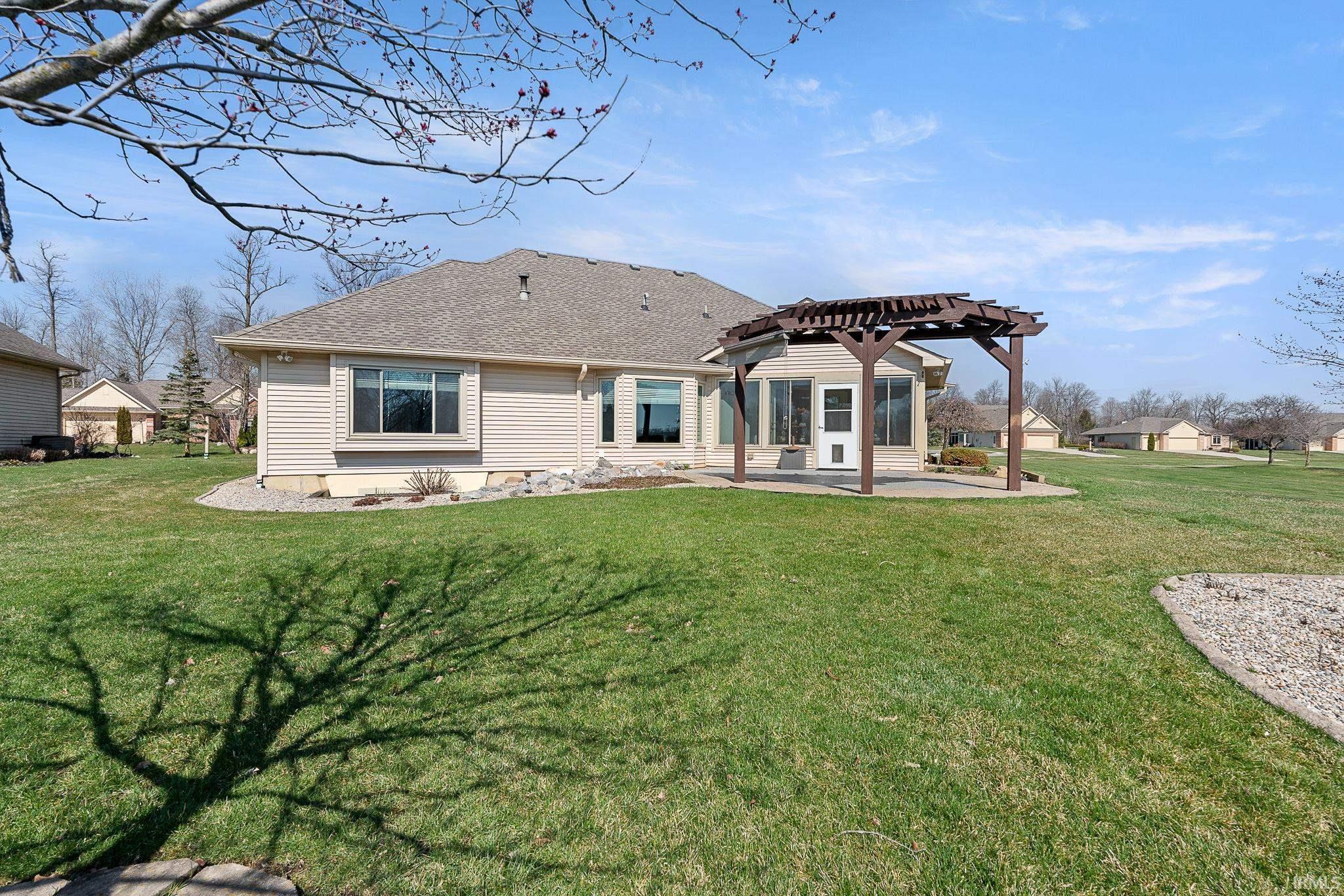 Back of property featuring a patio area, a pergola, a lawn, and a shingled roof