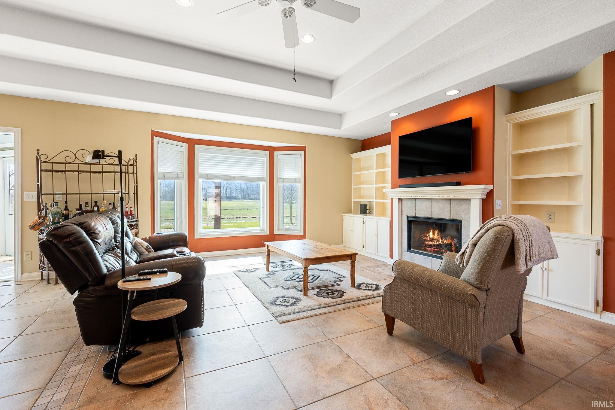 Living area featuring built in features, light tile patterned floors, recessed lighting, a tile fireplace, and ceiling fan