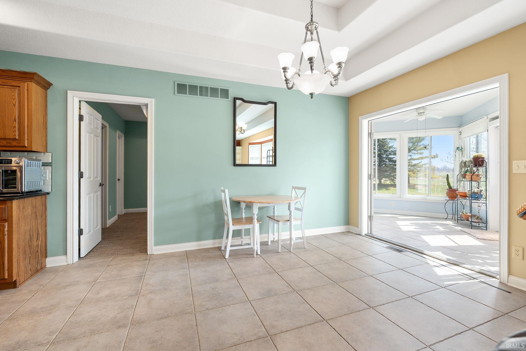 Dining space featuring a chandelier, light tile patterned floors, and a ceiling fan