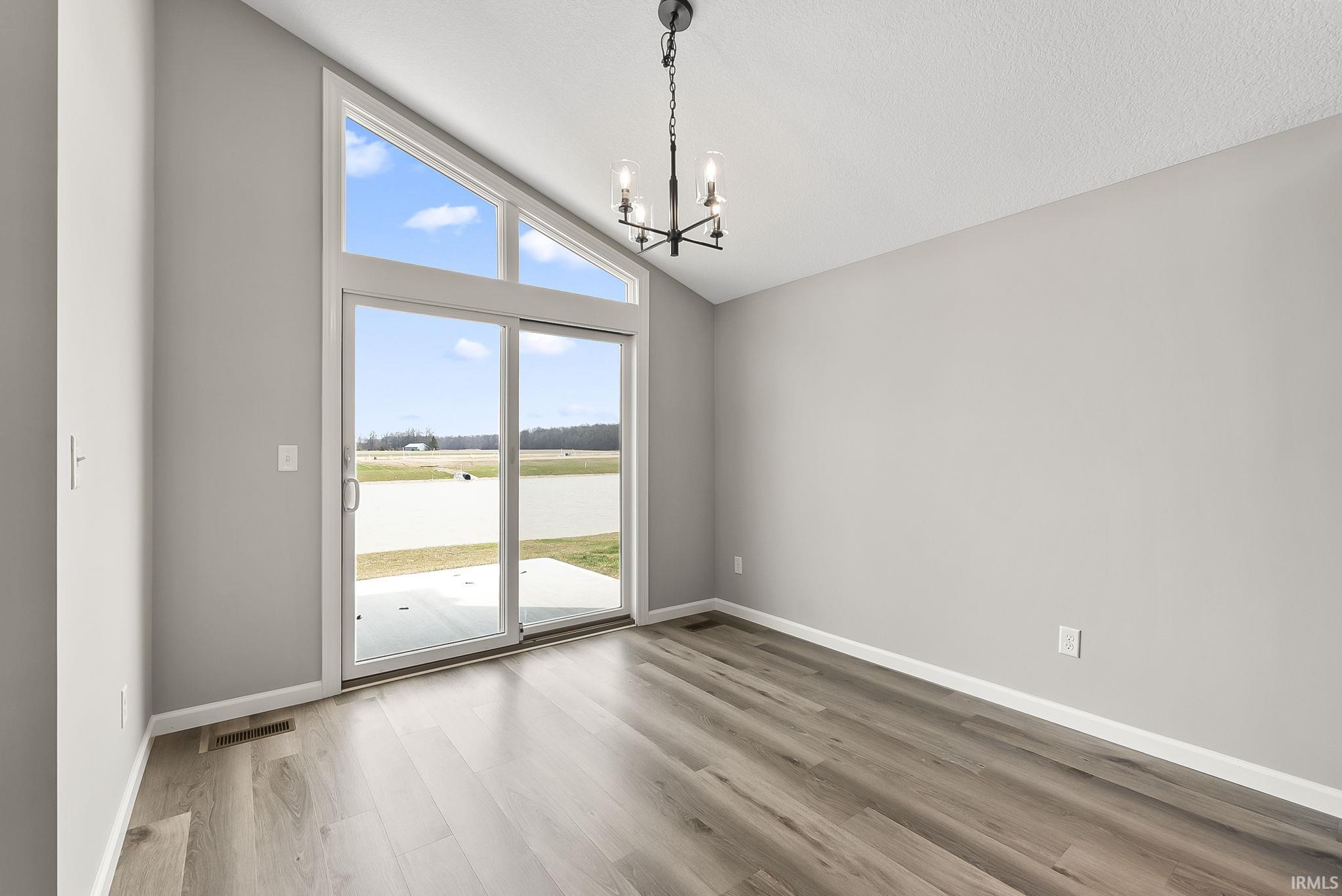 Unfurnished dining area with lofted ceiling, a chandelier, and light wood-type flooring