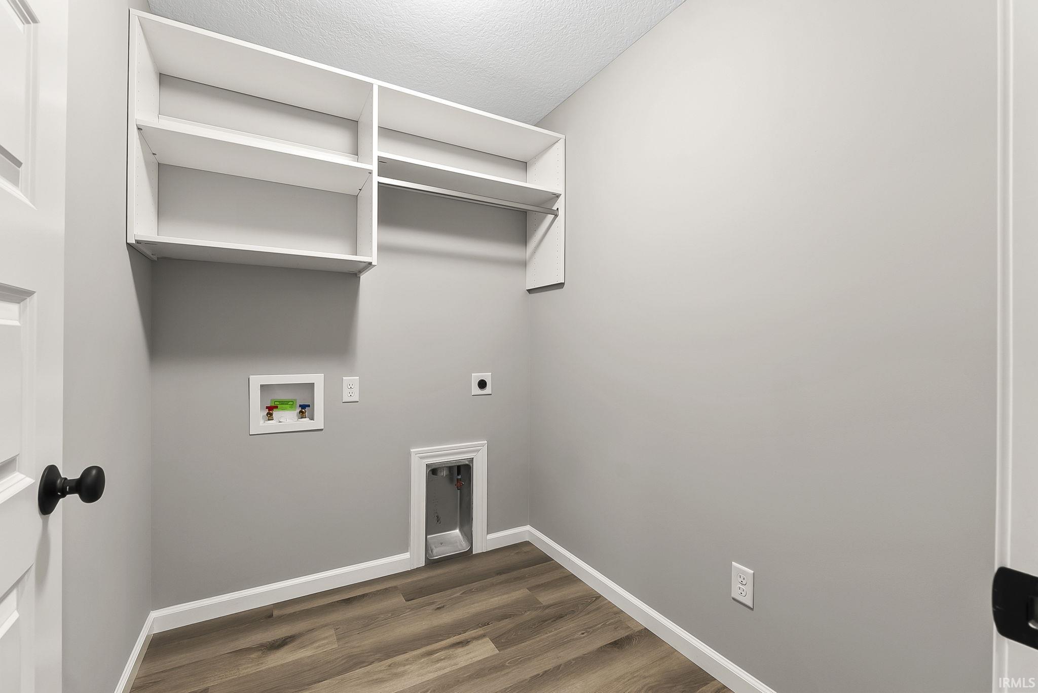 Laundry room with electric dryer hookup, dark wood-type flooring, hookup for a washing machine, and a textured ceiling