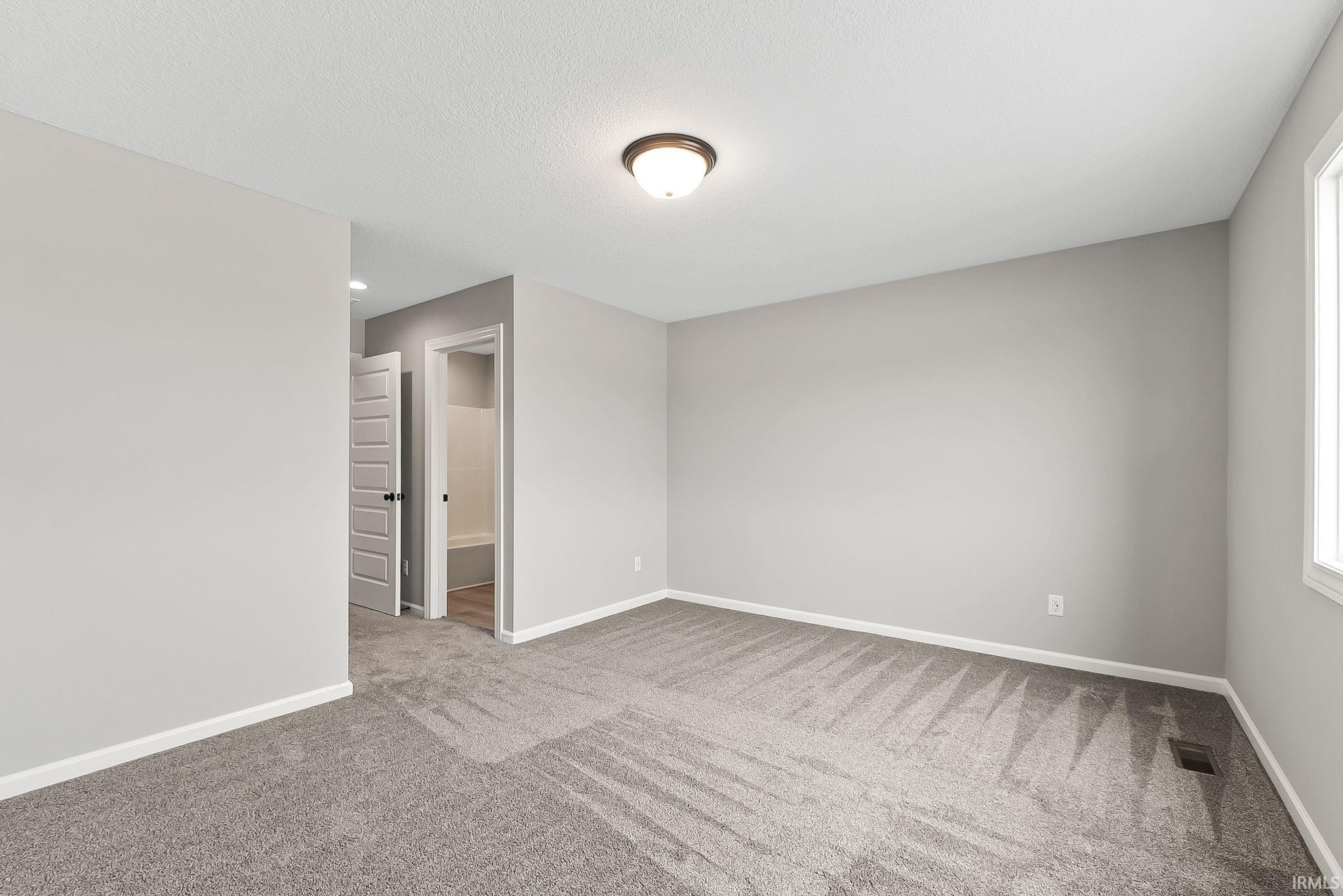 Spare room featuring baseboards and light colored carpet