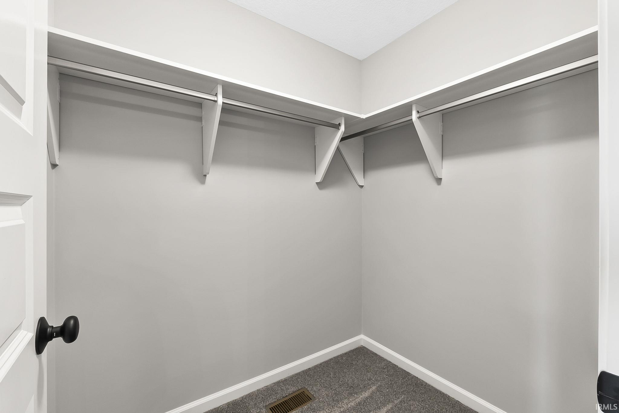 Walk in closet featuring dark carpet