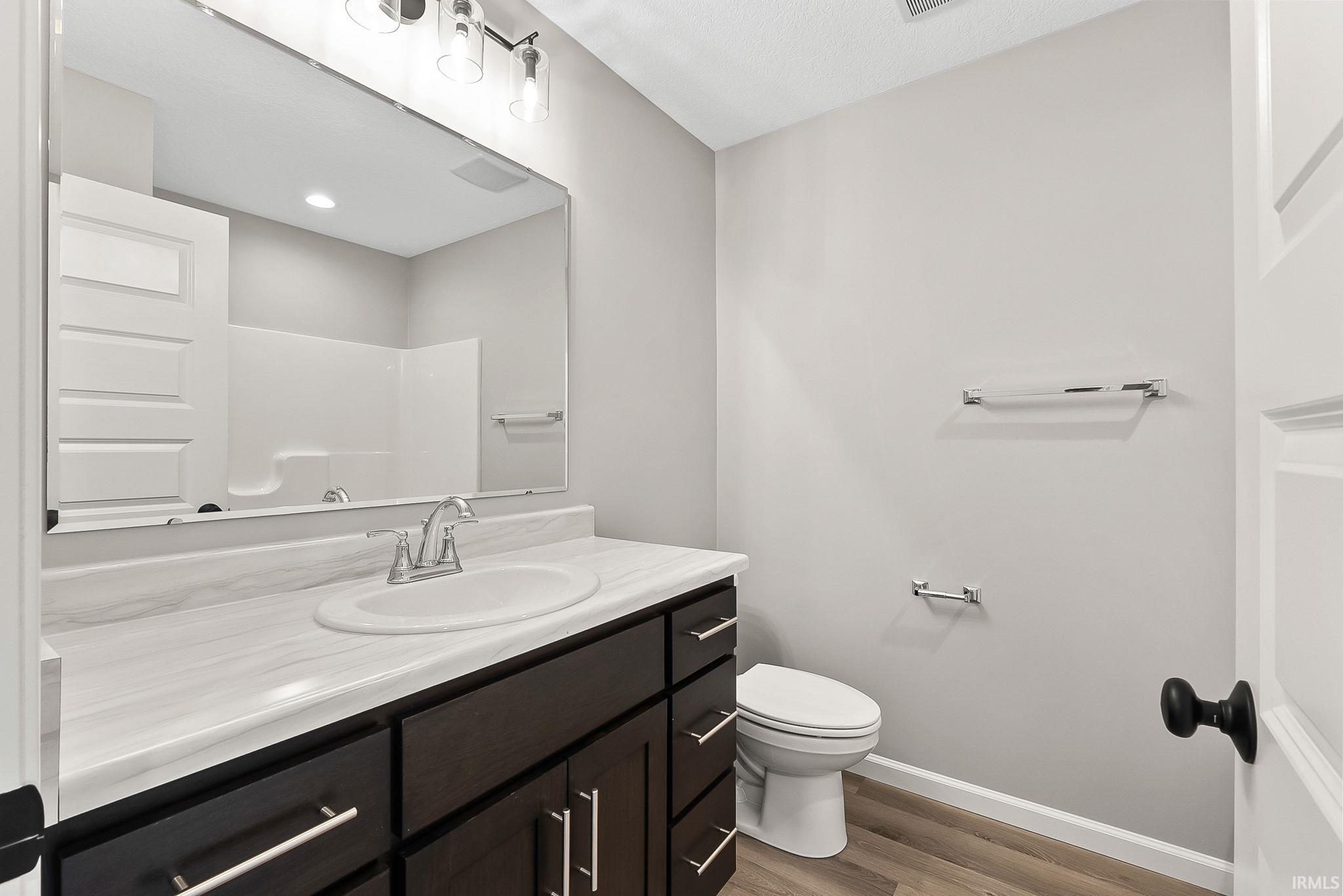 Full bath featuring vanity, light wood-style flooring, and a shower