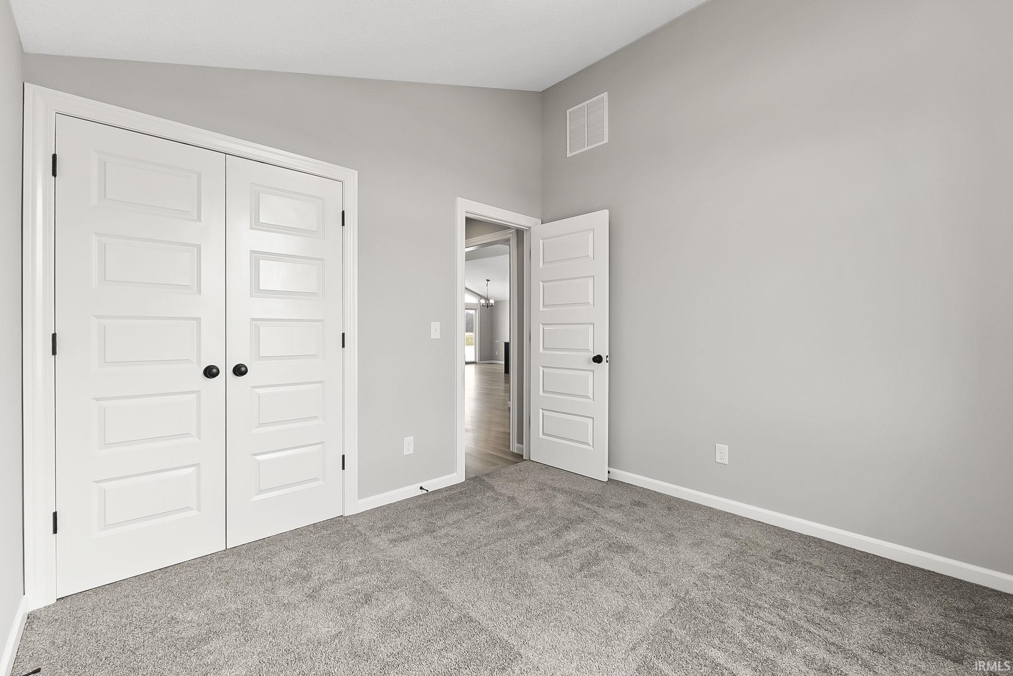 Unfurnished bedroom featuring carpet floors, a closet, and lofted ceiling