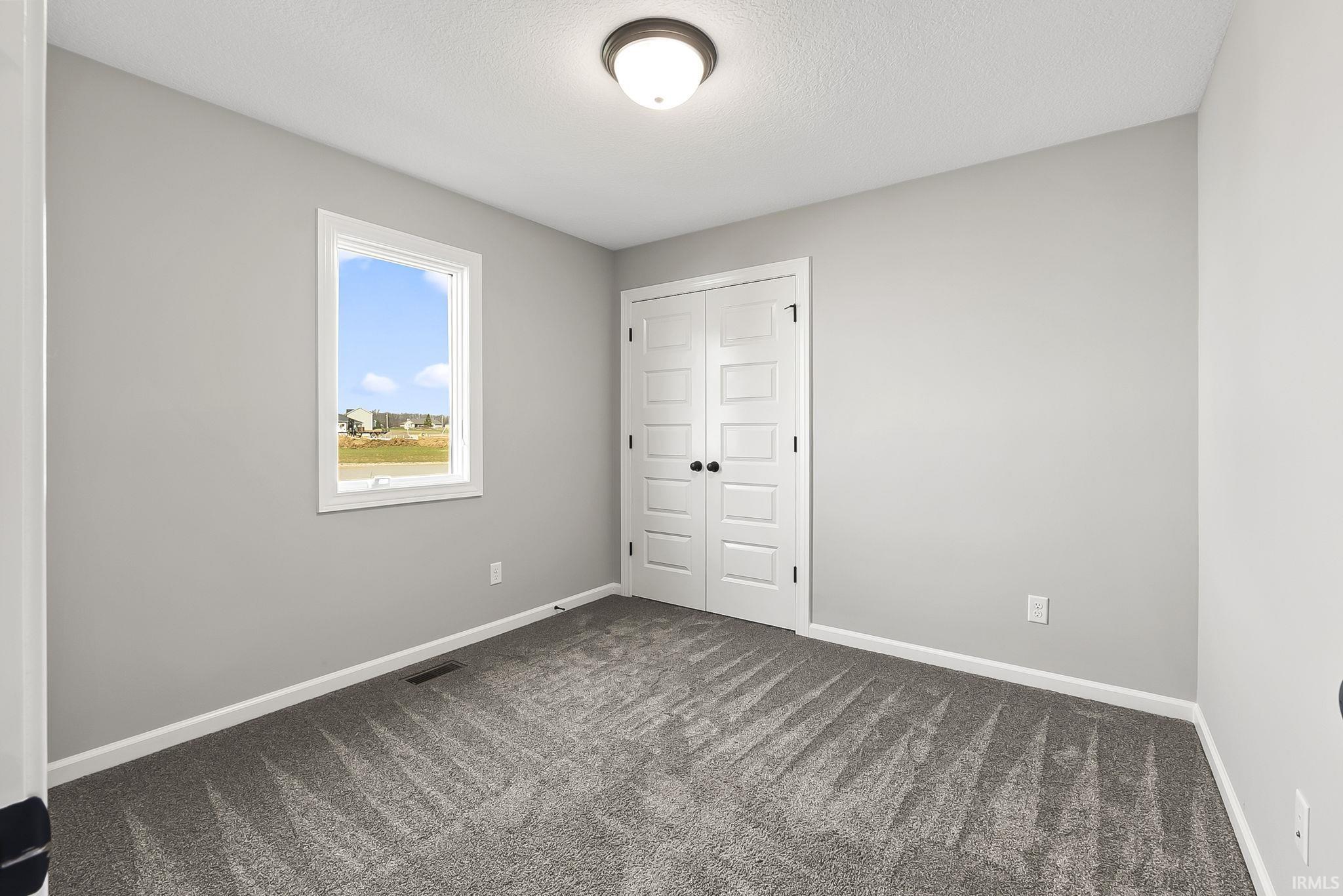 Unfurnished bedroom featuring a closet, dark colored carpet, and a textured ceiling