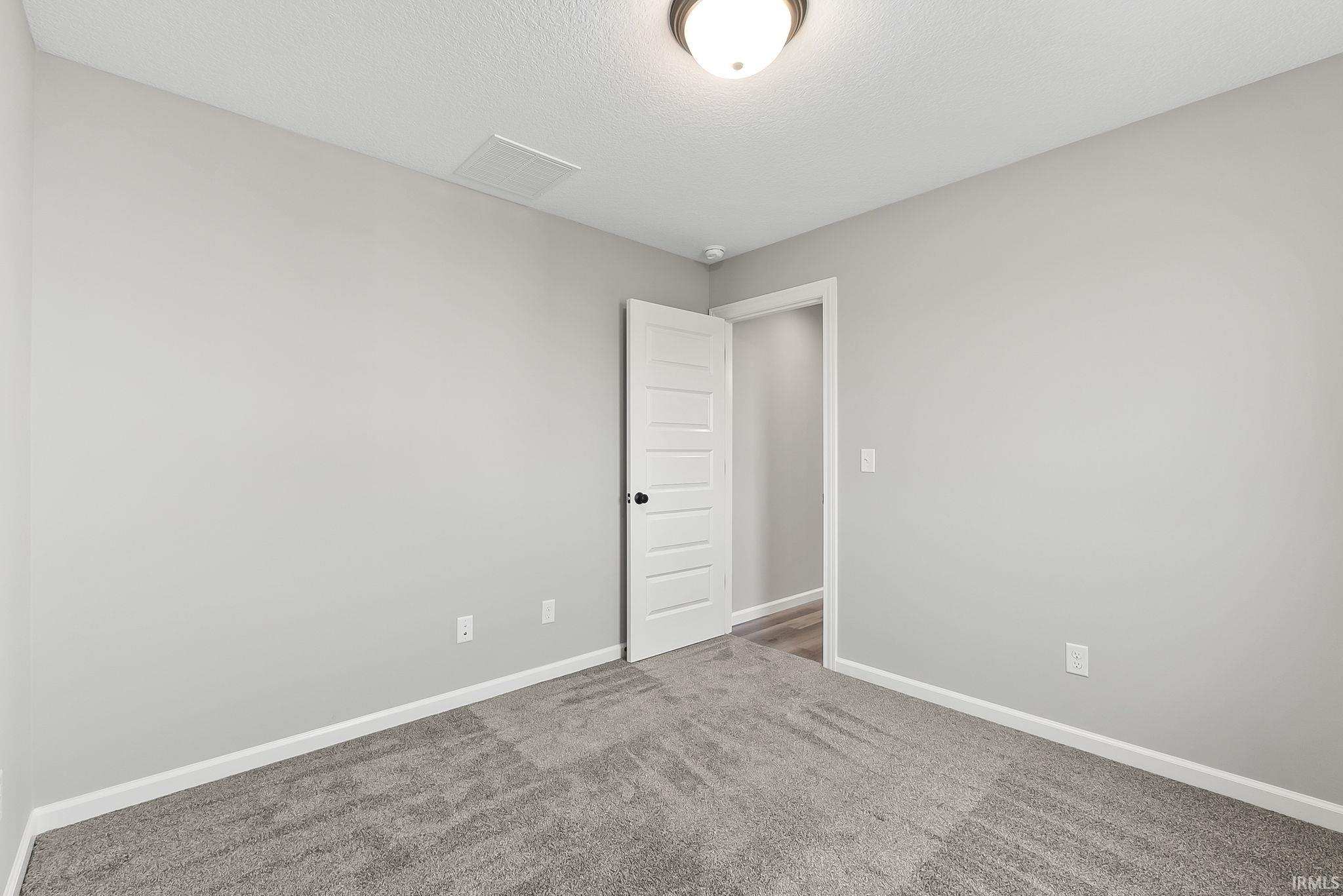 Carpeted empty room featuring baseboards and a textured ceiling