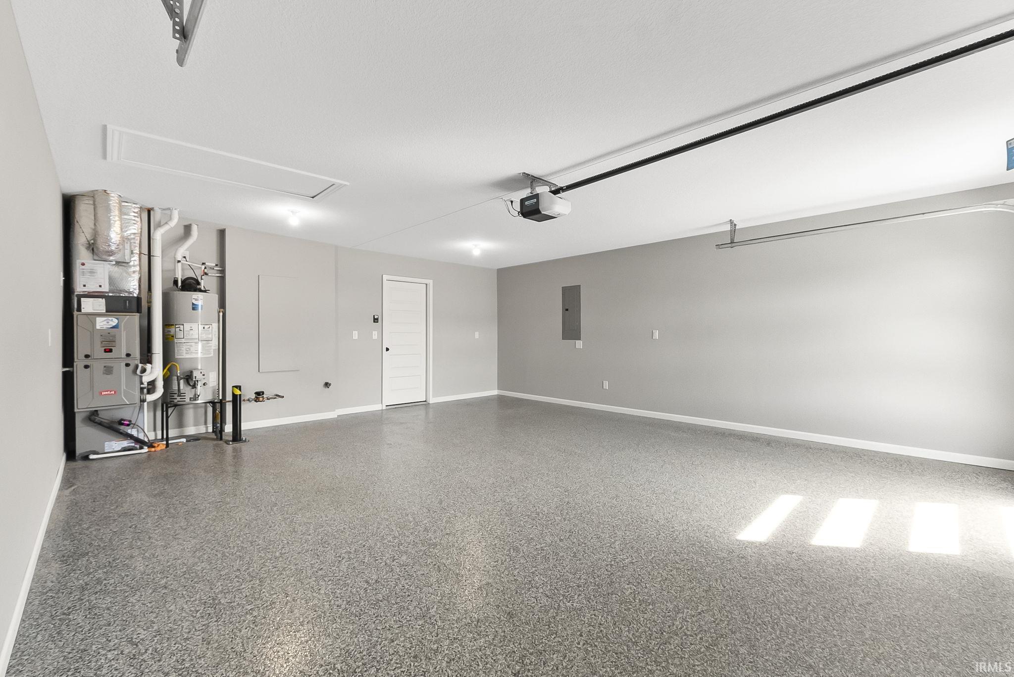 Garage featuring gas water heater, heating unit, and electric panel